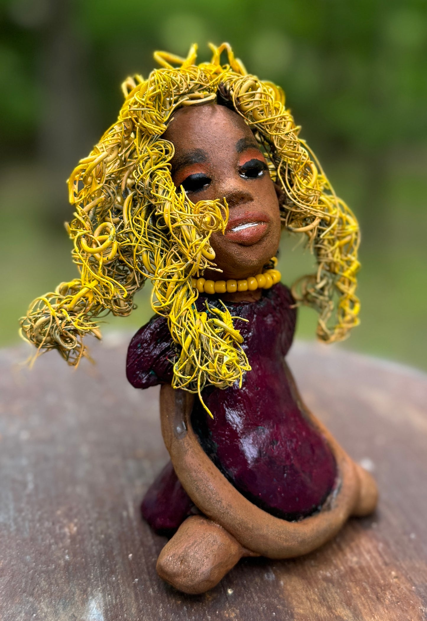 Kerri measures 6" x 4" x 3" and weighs 14ozs. She dons a stunning ruby red dress, her coiled yellow wire hair serving as her crown of glory. Poised in a yoga pose, her expression reflects curiosity. She is the perfect addition to the Herdew Collection, embodying adventure and risk-taking! Enjoy free shipping and check out our return policy.