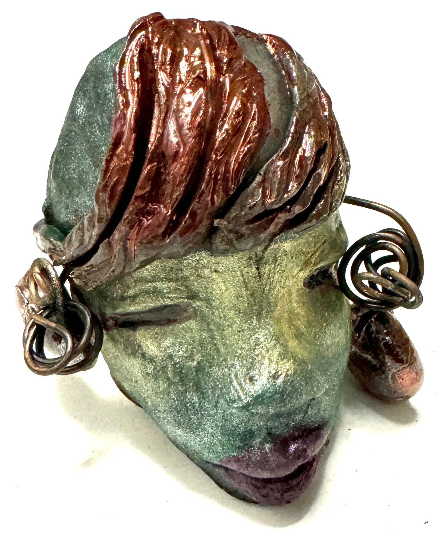 Monday weighs 3.2 oz and measures 3" by 4" in diameter. Her hair is copper-braided and her complexion is a light blueish green hue with purple lips. She is an ideal introductory piece from the HerDew mask collection.