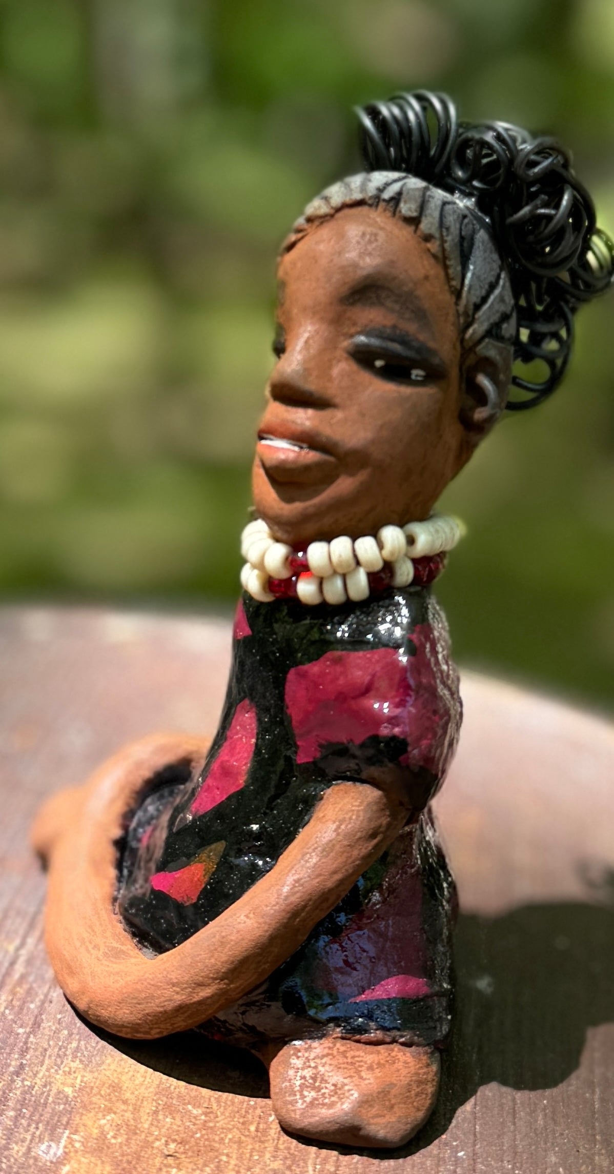 Gain a firsthand experience of the fearless Gwen from the Herdew Collection! This raku fired sculpture stands at an impressive 6" x 4" x 3" and weighs a bold 9.8 ozs. Gwen's striking striped ruby red dress and coiled wire hair, stretching over a foot, make for a captivating addition to any collection. Her confident outstretched arms and prayerful yoga pose embody a sense of adventure. Have questions? Contact us via instant messaging or chat. Check out our Shipping and Return policy.