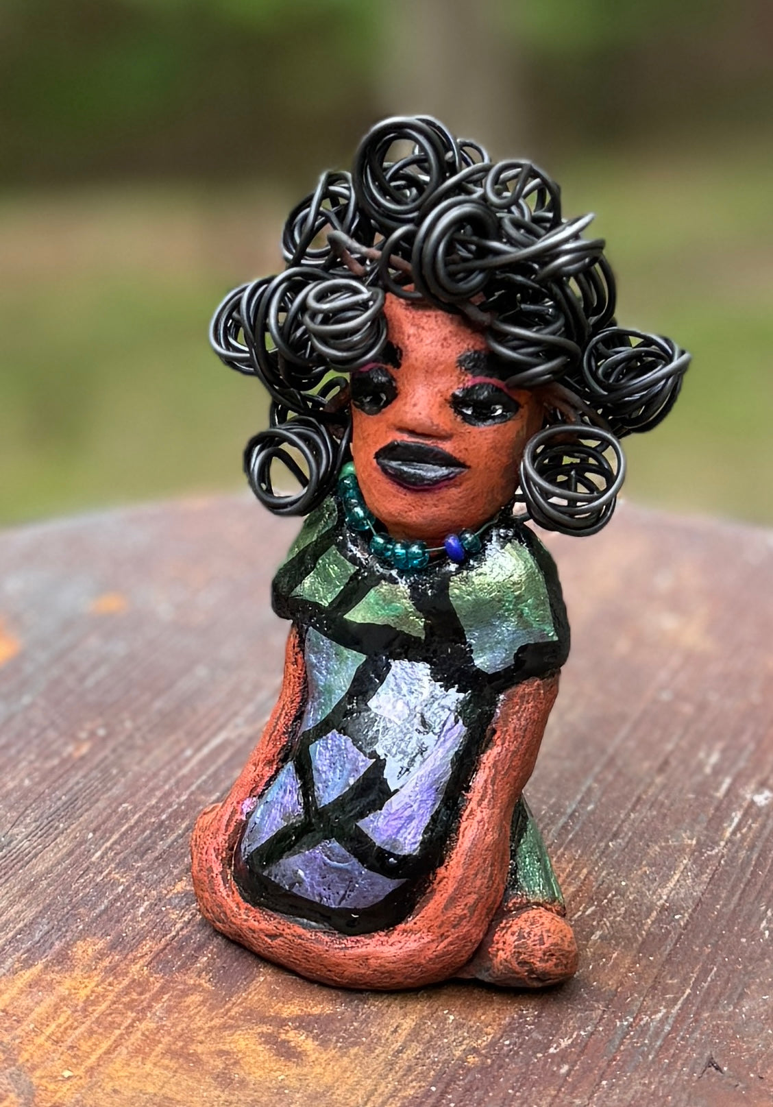 Discover Taci, the bold figurine standing at 5.5" tall and weighing only 8.6 ozs, adorned in a striking black and green African print dress. With her hair styled in coils and her hands calmly resting in a yoga pose, Taci emanates confidence. Join the Herdew Collection and embark on an exciting journey with our complimentary shipping and customer-friendly return policy. Don't hesitate to claim this unique treasure!