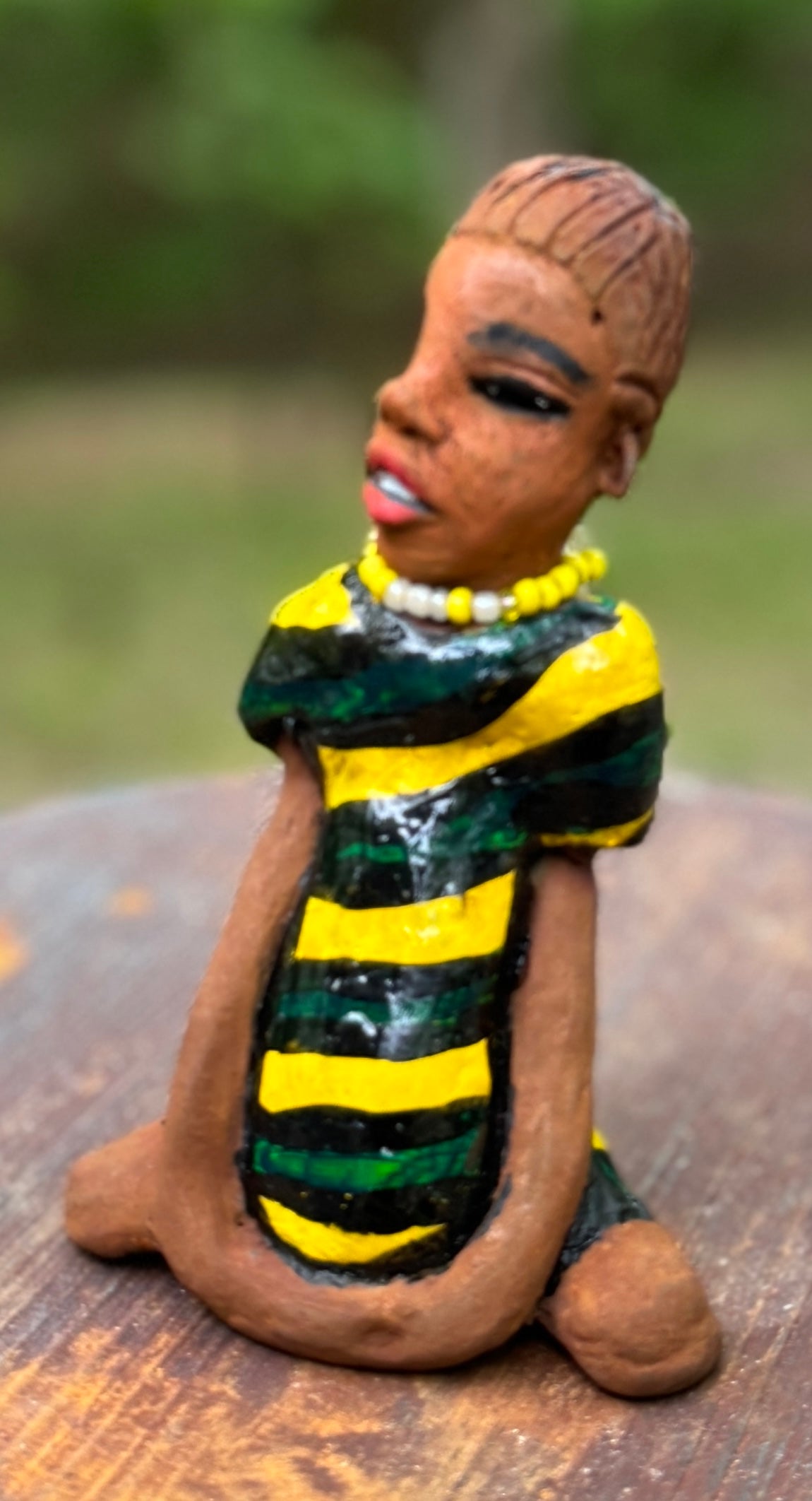 Experience the bold and fearless Kia from the Herdew Collection! This raku fired sculpture stands tall at 6" x 4" x 3" and weighs a brave 9.4 ozs. Clothed in a striking yellow and green dress, Kia's coiled wire hair stretches over 1 foot. With confident outstretched arms, she strikes a yoga pose. Begin your collection with the captivating Kitty and embrace adventure!