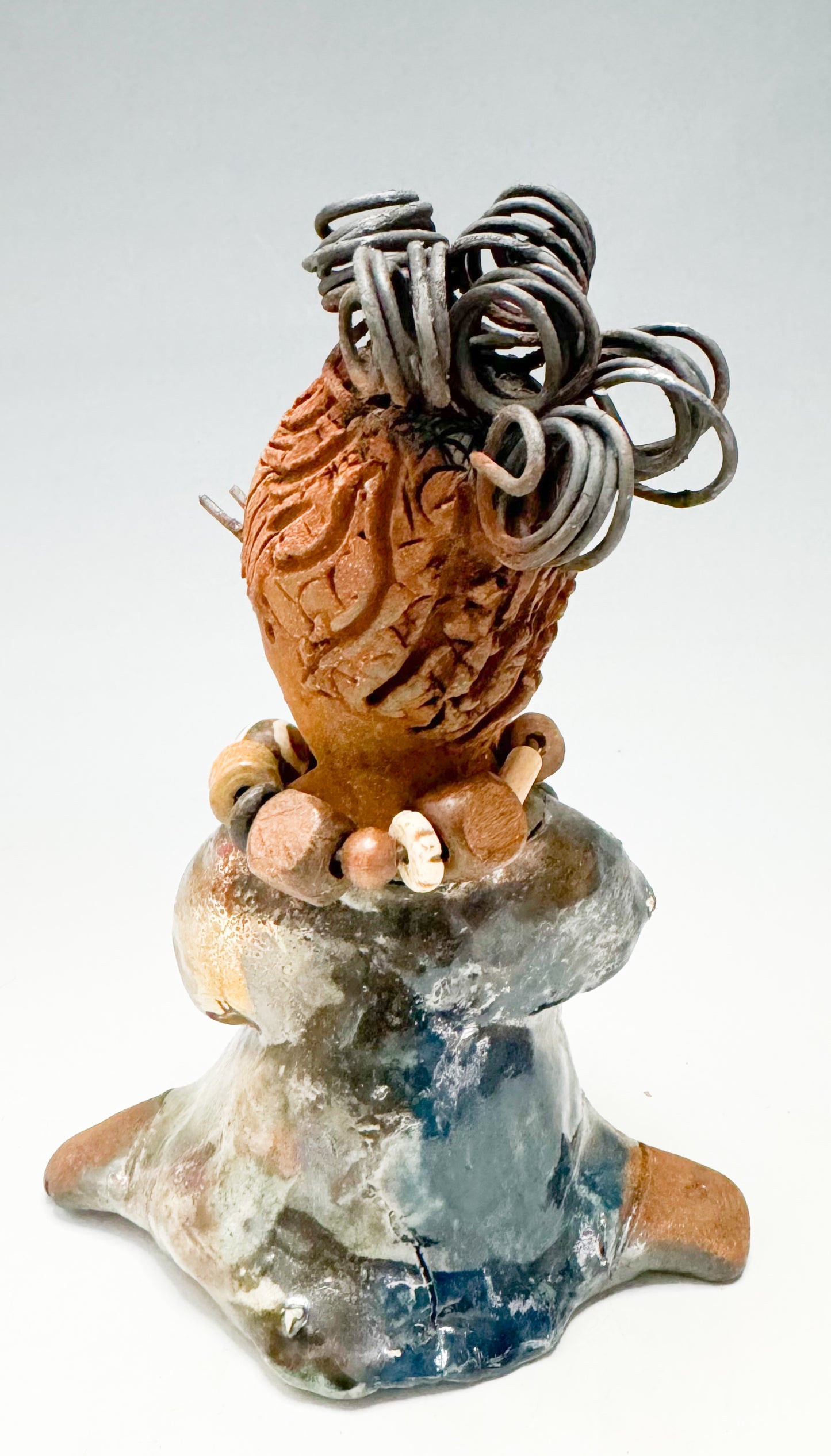 Introducing Kitty, the fearless one standing at 6" x 4" x 3" and weighing 12 ozs! Adorned in a stunning metallic gold dress, Kitty's coiled wire hair measures over 3 feet. Poised in a yoga pose, her long arms rest confidently at her lap. Start your collection off strong with the captivating Kitty from the Herdew Collection
