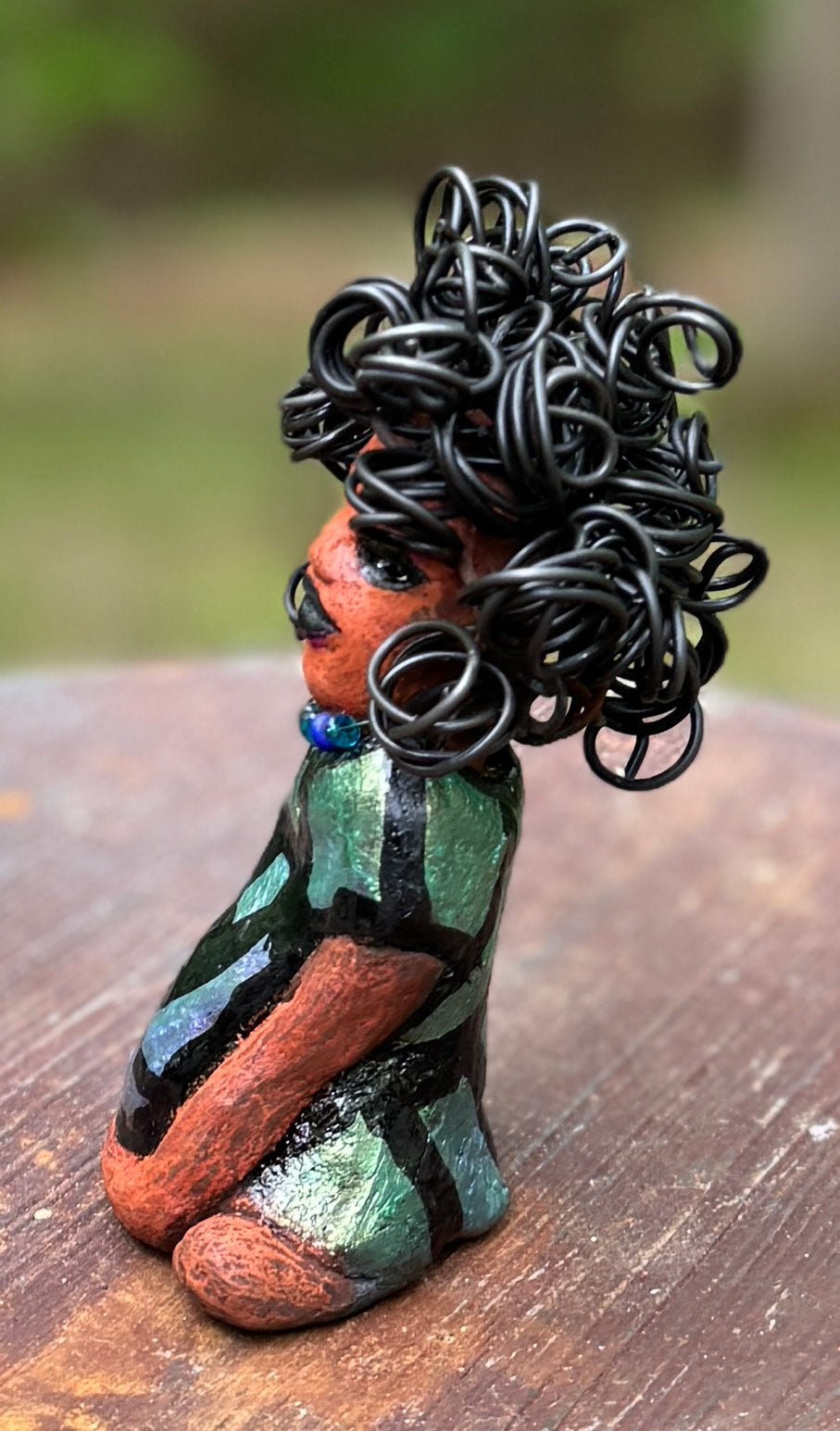 Discover Taci, the bold figurine standing at 5.5" tall and weighing only 8.6 ozs, adorned in a striking black and green African print dress. With her hair styled in coils and her hands calmly resting in a yoga pose, Taci emanates confidence. Join the Herdew Collection and embark on an exciting journey with our complimentary shipping and customer-friendly return policy. Don't hesitate to claim this unique treasure!