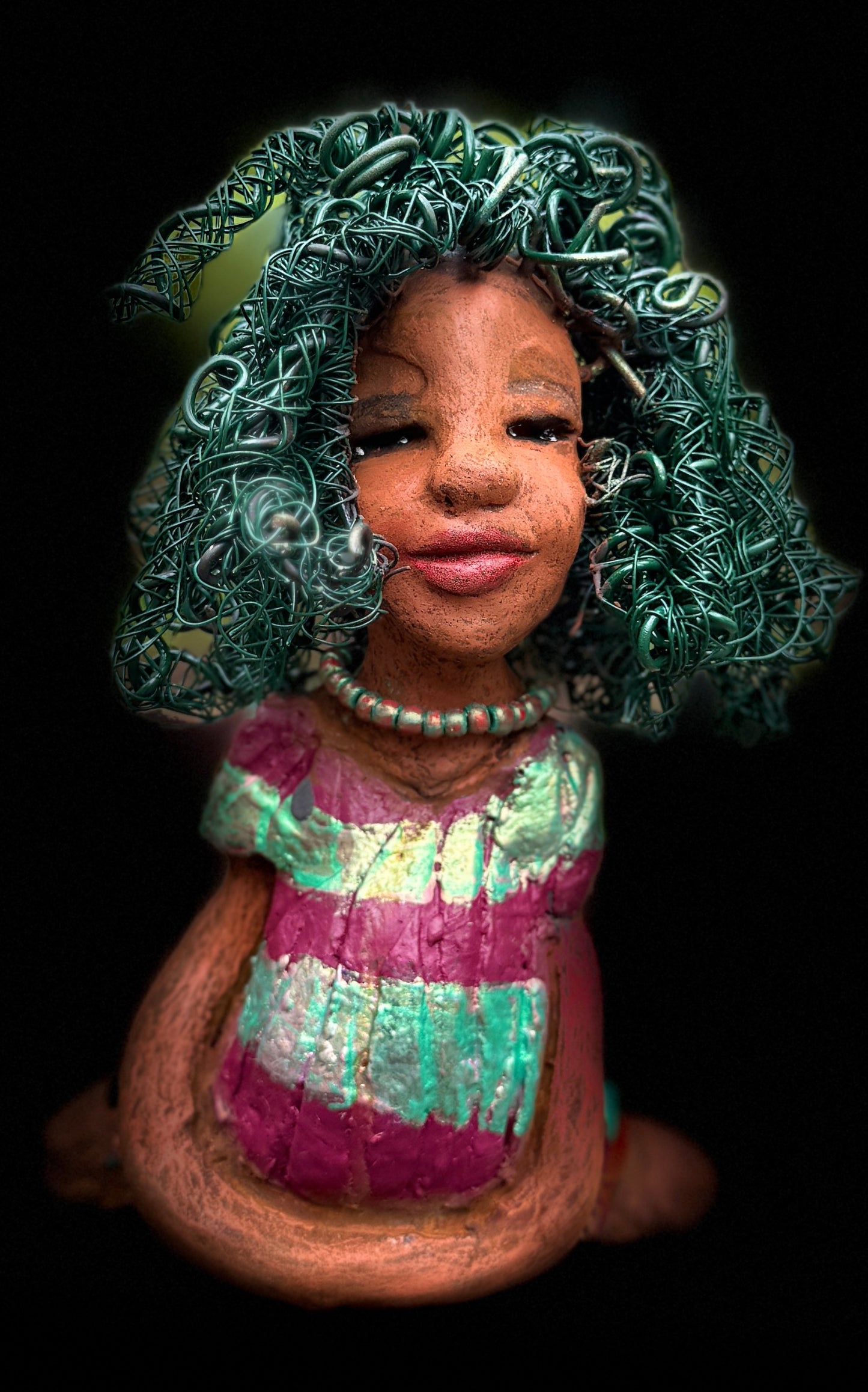 Coco is a 7.5" x 4" x 3" figurine that weighs 1 lb and wears a stunning red and green dress with stripes. Her wire hair is intricately coiled and adds to her regal appearance. Poised in a yoga pose, Coco's expression exudes curiosity, making her a perfect addition to the Herdew Collection.