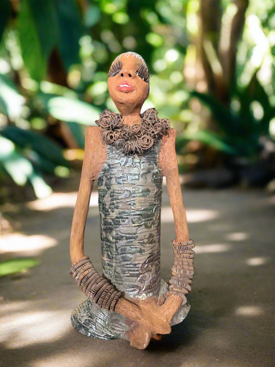 Sophia is an art piece standing at a height of 21 inches and weighing 9 pounds. It is a raku fire sculpture created as a tribute to my mentor, who has greatly impacted my journey as an art teacher. Taking inspiration from individuals in my life, Sophia boasts a striking copper patina on its dress, along with affectionate arms and lengthy eyelashes