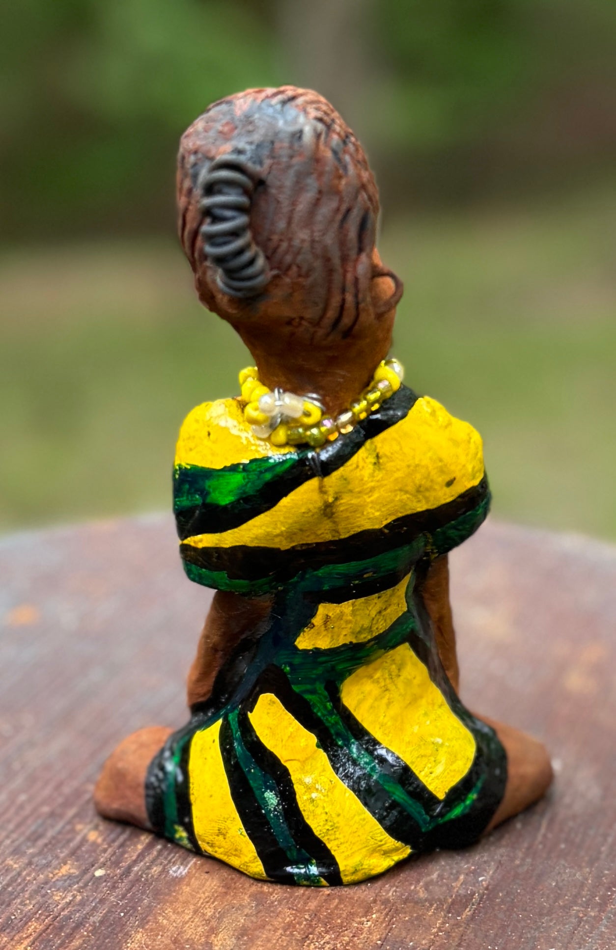 Experience the bold and fearless Kia from the Herdew Collection! This raku fired sculpture stands tall at 6" x 4" x 3" and weighs a brave 9.4 ozs. Clothed in a striking yellow and green dress, Kia's coiled wire hair stretches over 1 foot. With confident outstretched arms, she strikes a yoga pose. Begin your collection with the captivating Kitty and embrace adventure!