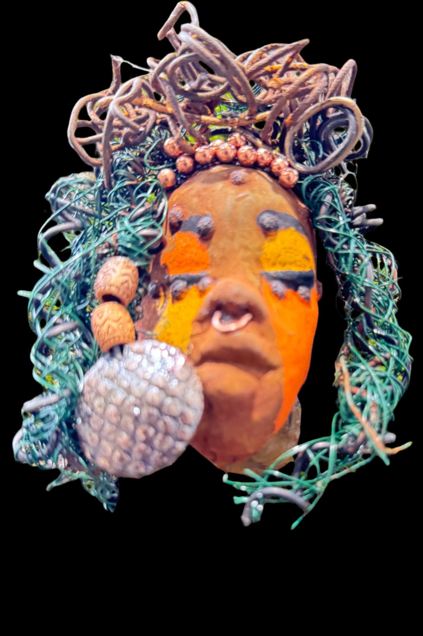 Adda's unique design against a mossy tree bark backdrop is sure to catch your eye. This 3” x 5” 6oz. mixed media raku fire mask, crafted with 15 feet of 24 and 16 gauge wire, adds a touch of elegance to your HerDew mask collection. With a copper nose ring, three-colored complexion, and a large Raku fired earring with two wooden beads, Adda is a must-have for any mask enthusiast.