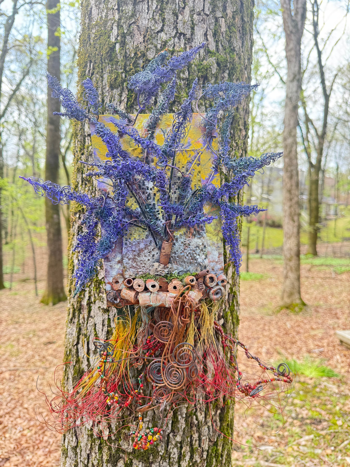 Experience the whimsical world of Purple Dusk with this mixed media landscape. Measuring 20"x16", it combines 16- and 24-gauge wire with handmade Raku fire beads, and even includes a RAKU fired and hand painted texture tile on a 7"x5" wood base. Let the sun peek through the vibrant purple dusk leaves and transport you to a lazy warm summer day.