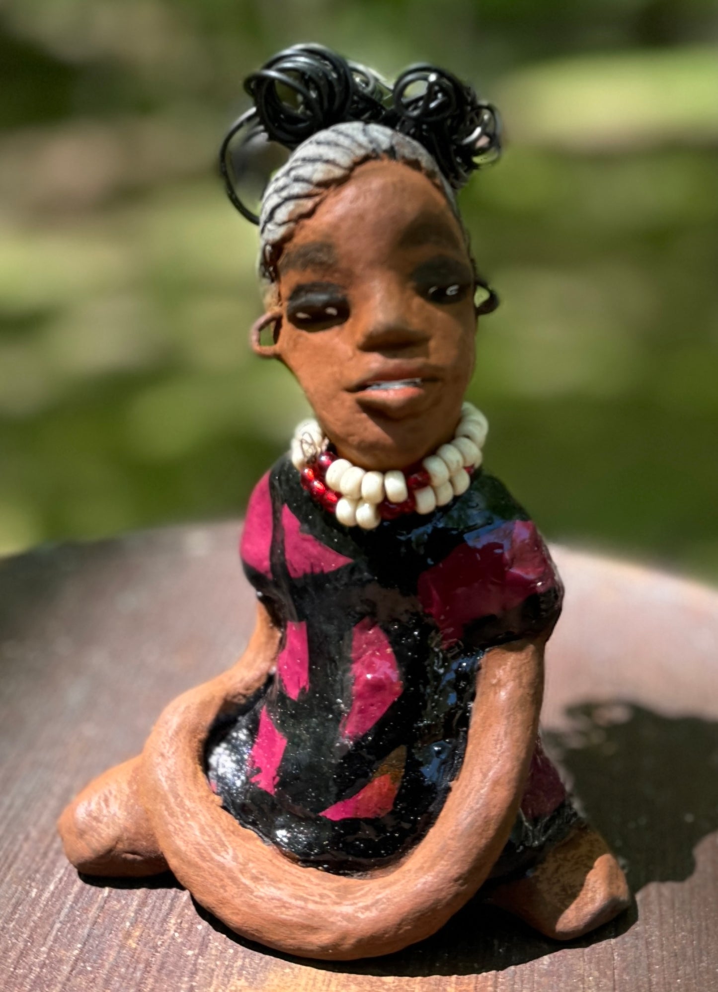 Gain a firsthand experience of the fearless Gwen from the Herdew Collection! This raku fired sculpture stands at an impressive 6" x 4" x 3" and weighs a bold 9.8 ozs. Gwen's striking striped ruby red dress and coiled wire hair, stretching over a foot, make for a captivating addition to any collection. Her confident outstretched arms and prayerful yoga pose embody a sense of adventure. Have questions? Contact us via instant messaging or chat. Check out our Shipping and Return policy.