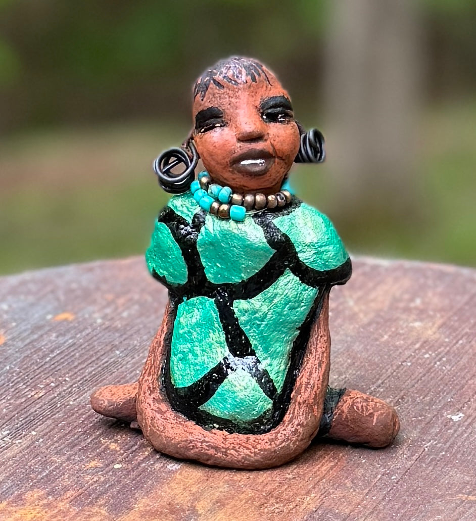 Discover Nala, the bold figurine standing at 4.5" tall and weighing only 5.6 ozs, adorned in a striking black and green African print dress. With her hair styled in coils and her hands calmly resting under her head in a yoga pose, Nala emanates confidence. Join the Herdew Collection and embark on an exciting journey with our complimentary shipping and customer-friendly return policy. Don't hesitate to claim this unique treasure!