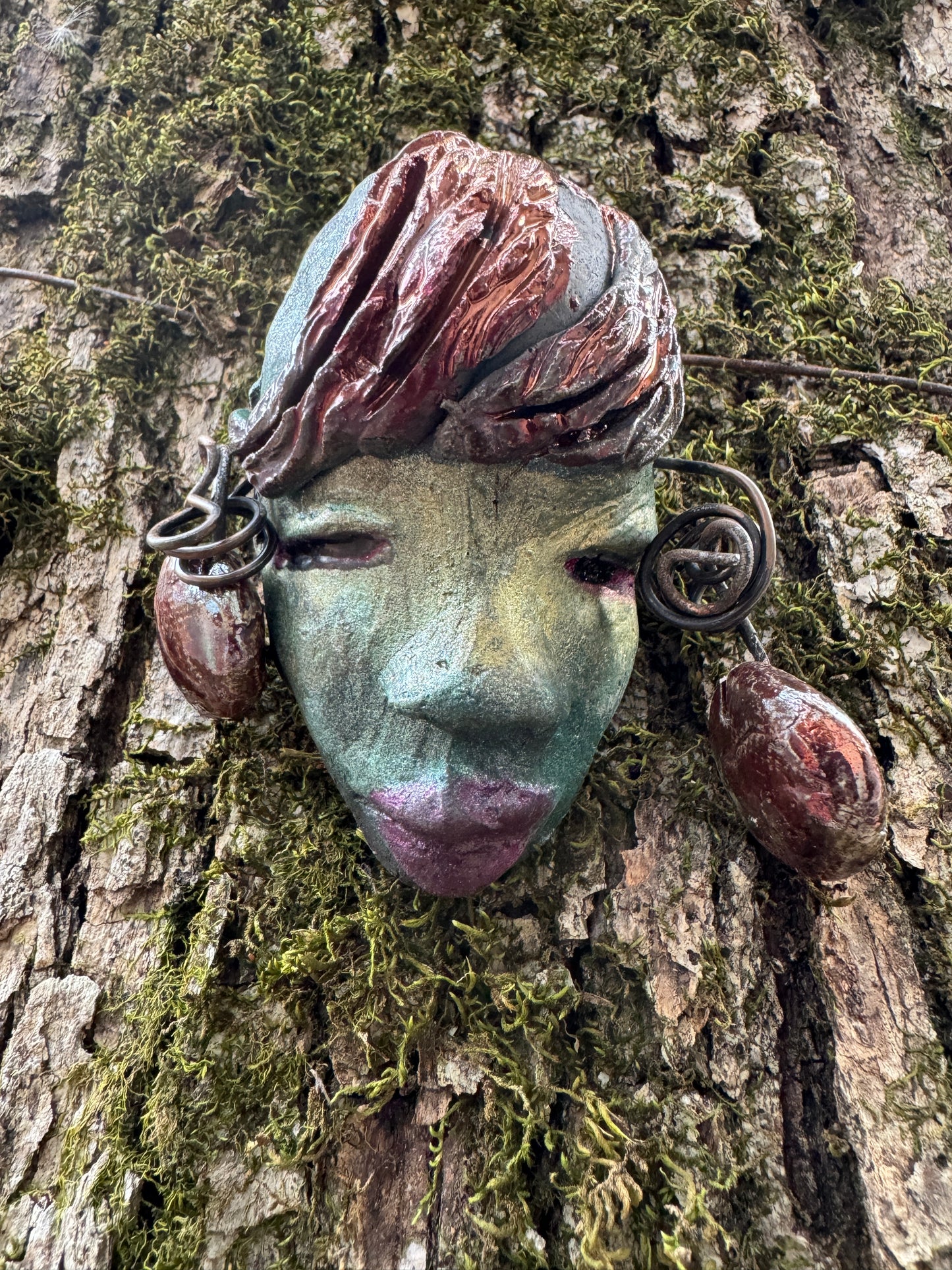 Monday weighs 3.2 oz and measures 3" by 4" in diameter. Her hair is copper-braided and her complexion is a light blueish green hue with purple lips. She is an ideal introductory piece from the HerDew mask collection.