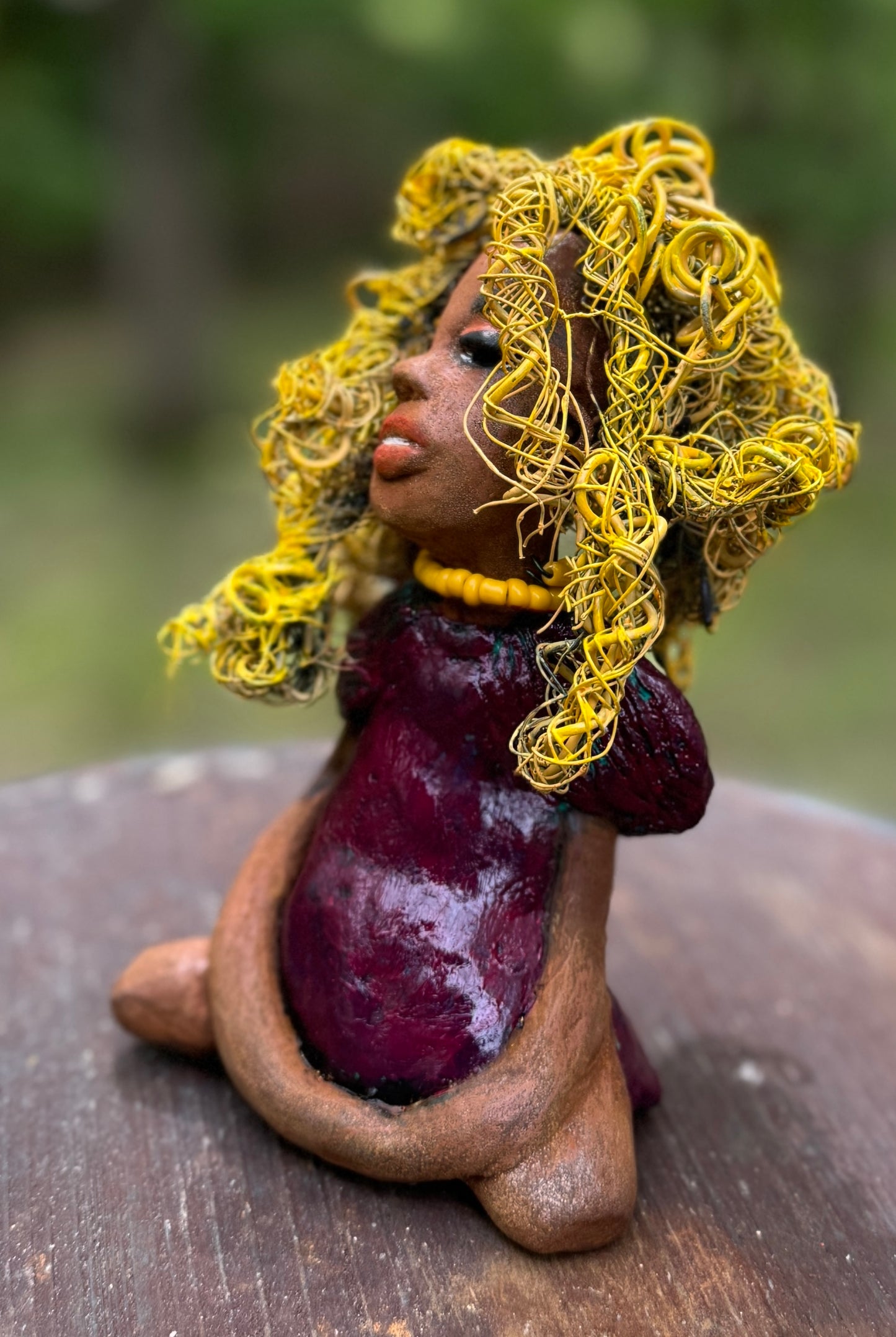 Kerri measures 6" x 4" x 3" and weighs 14ozs. She dons a stunning ruby red dress, her coiled yellow wire hair serving as her crown of glory. Poised in a yoga pose, her expression reflects curiosity. She is the perfect addition to the Herdew Collection, embodying adventure and risk-taking! Enjoy free shipping and check out our return policy.