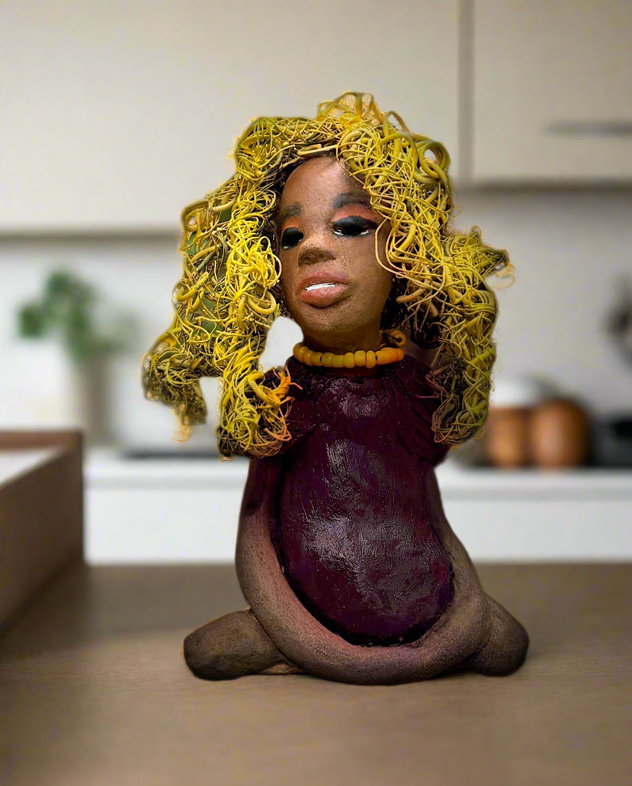 Kerri measures 6" x 4" x 3" and weighs 14ozs. She dons a stunning ruby red dress, her coiled yellow wire hair serving as her crown of glory. Poised in a yoga pose, her expression reflects curiosity. She is the perfect addition to the Herdew Collection, embodying adventure and risk-taking! Enjoy free shipping and check out our return policy.