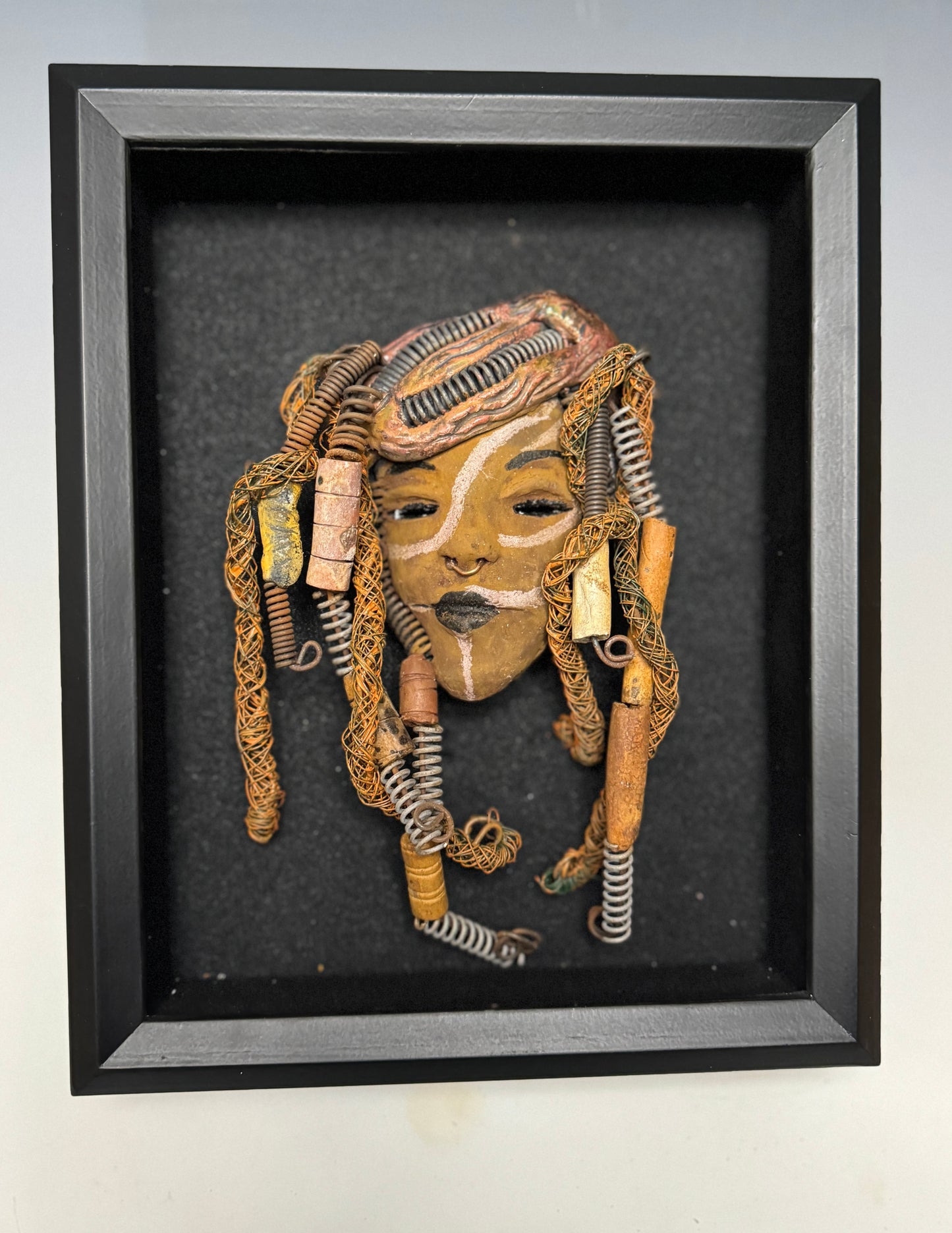 Weighing 6 oz and with a diameter of 5" by 8", Addo adds mystic to any wall, tree or shadowbox. His earthy braids, honey brown complexion and dark lips make him the perfect first piece from the HerDew mask collection. Shadow box not included with Jaleni's purchase.
