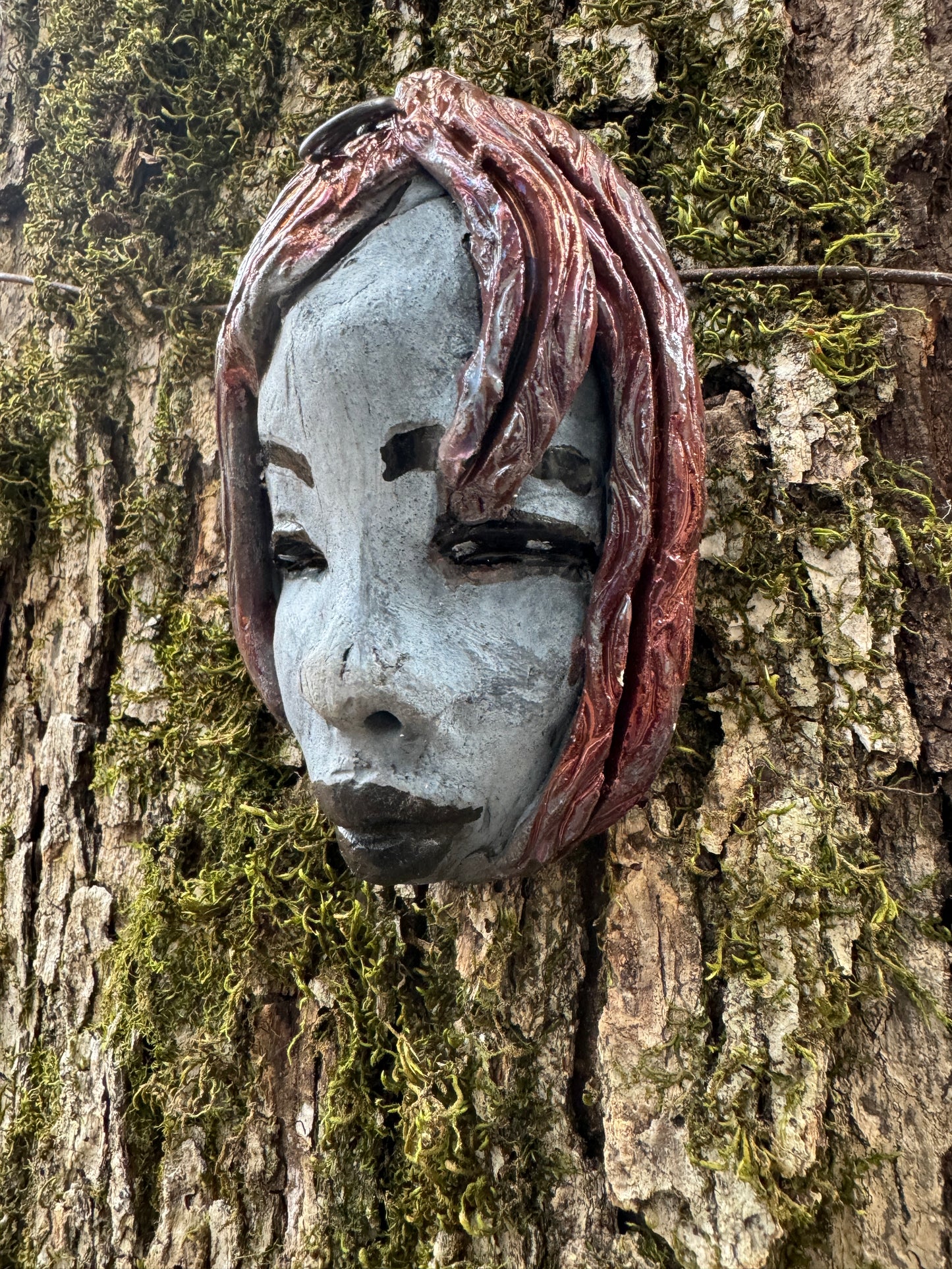 Mia weighs 4 oz and measures 4" by 3" in diameter. Her hair is copper-braided and her complexion is a light grayish blue hue with black lips. She is an ideal introductory piece from the HerDew mask collection.