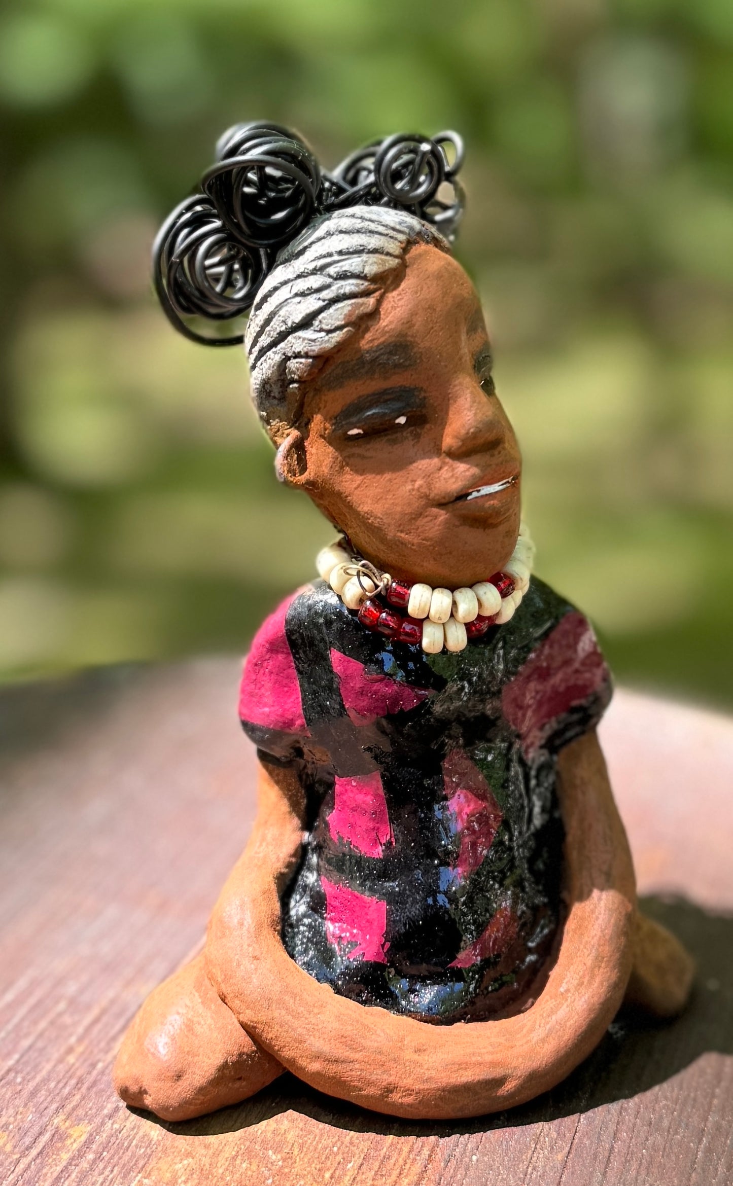 Gain a firsthand experience of the fearless Gwen from the Herdew Collection! This raku fired sculpture stands at an impressive 6" x 4" x 3" and weighs a bold 9.8 ozs. Gwen's striking striped ruby red dress and coiled wire hair, stretching over a foot, make for a captivating addition to any collection. Her confident outstretched arms and prayerful yoga pose embody a sense of adventure. Have questions? Contact us via instant messaging or chat. Check out our Shipping and Return policy.