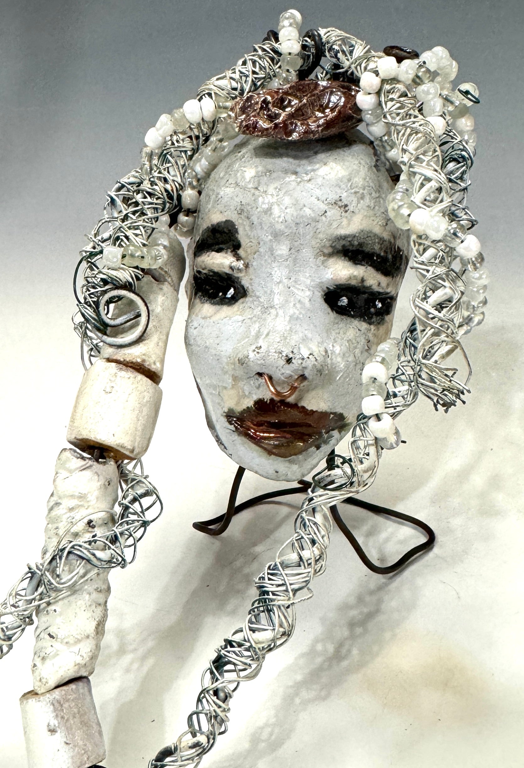 Faye is an absolutely stunning 4" x 4", 4.2 oz. Raku-fired mask with a white complexion, intricate beaded hair, and a one-of-a-kind portrait setting of a majestic tree. She's sure to make a statement indoors or outdoors - an artful gift for nature admirers and décor fans alike!