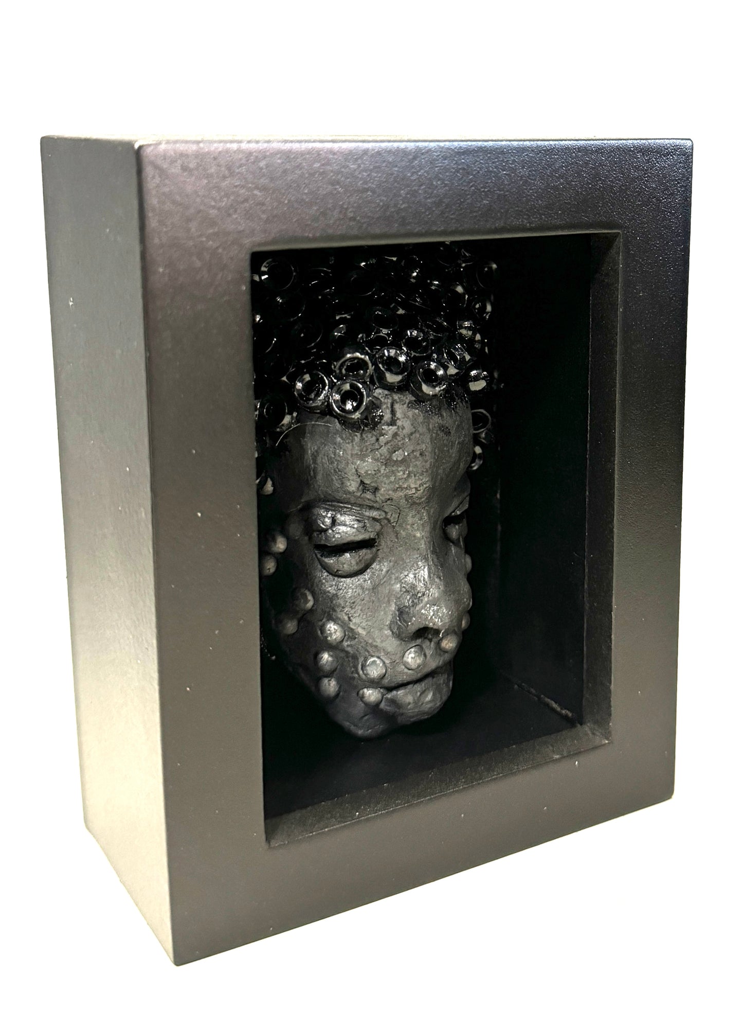Randy is a mask that is raku fired and is enclosed in a 4“ x 4“ black shadowbox. He has over 50 pony beads as hair. He has over 50 pony beads as hair!