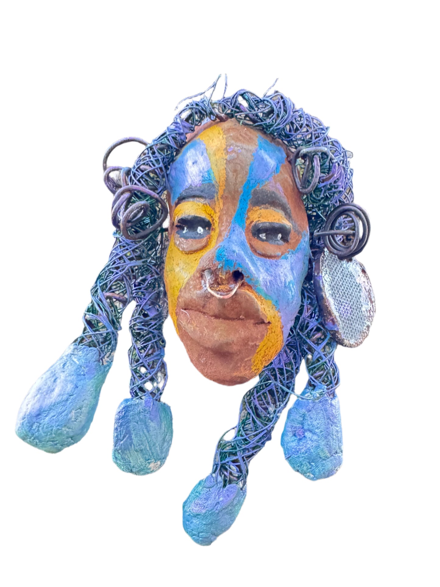 Esi is a lightweight 4 x 6" mixed media raku fire mask that combines a striking design with 24 and 16 gauge wire, 5 intricate blue tribal beads, and over 15 feet of wire. It can be proudly displayed against a solid black or white background, or for an even more impressive effect, consider a backdrop featuring lush, mossy trees.