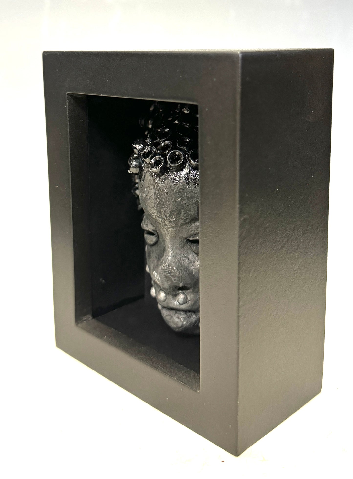 Randy is a mask that is raku fired and is enclosed in a 4“ x 4“ black shadowbox. He has over 50 pony beads as hair. He has over 50 pony beads as hair!