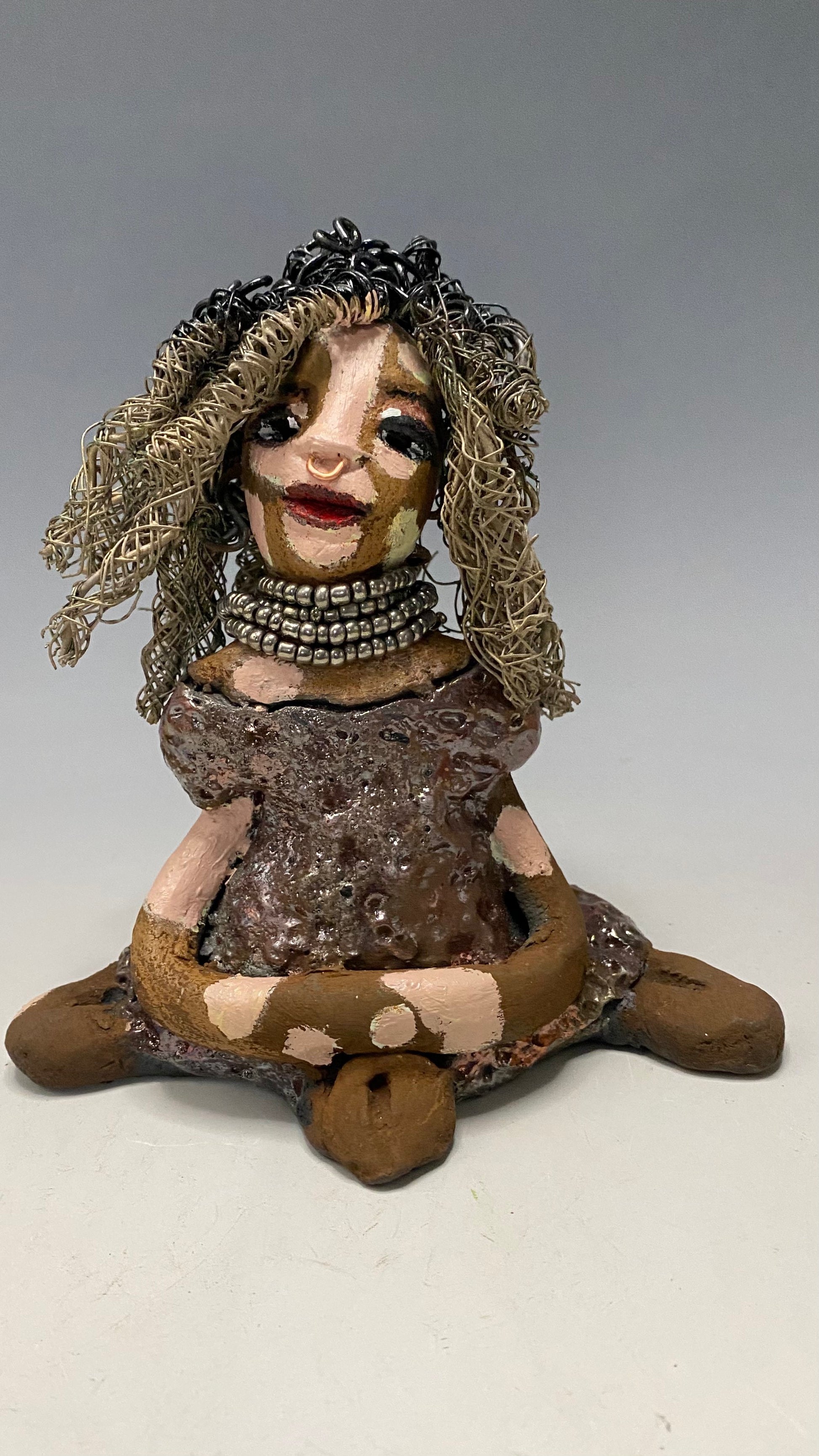 Anita stands 6.5" x 6" x 3" and weighs 1.3 lbs., with vitiligo. She loves the skin she's in! Her lips are painted with a warm ruby red, and long twisted white and gold wire locs that extend to her waist give her a unique style. Her dress is finished with a copper-antique glaze and over 75 feet of 16 and 24 gauge wire. Her bright eyes evoke a sense of hope. Add Anita to your family and she'll sure to be a conversation starter. Have questions? Ask away!