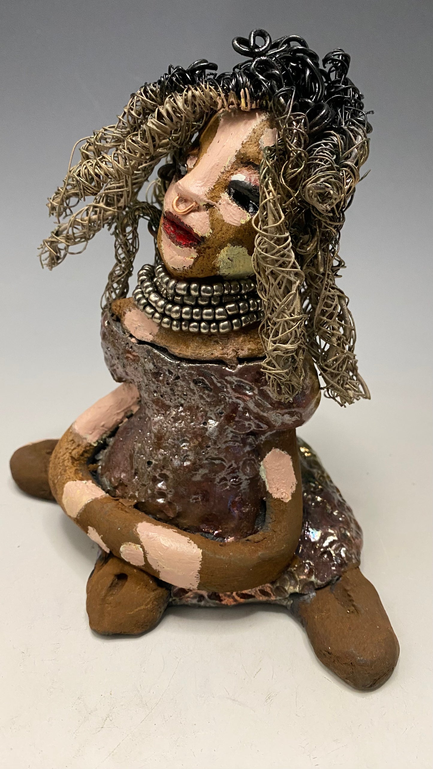 Anita stands 6.5" x 6" x 3" and weighs 1.3 lbs., with vitiligo. She loves the skin she's in! Her lips are painted with a warm ruby red, and long twisted white and gold wire locs that extend to her waist give her a unique style. Her dress is finished with a copper-antique glaze and over 75 feet of 16 and 24 gauge wire. Her bright eyes evoke a sense of hope. Add Anita to your family and she'll sure to be a conversation starter. Have questions? Ask away!