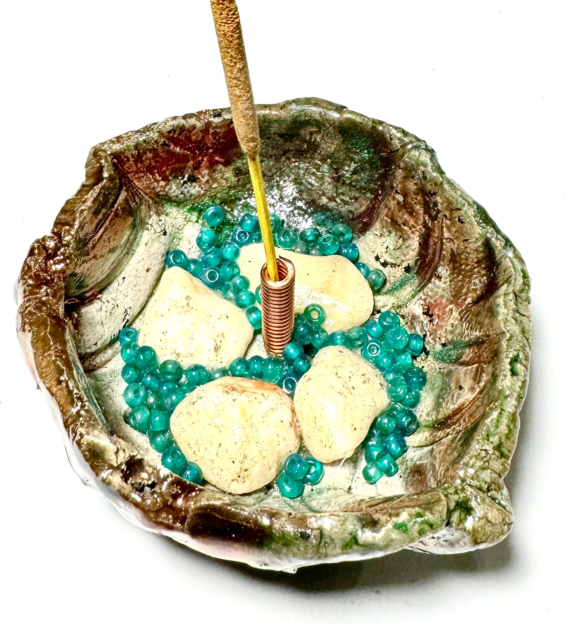 This 1" x 3" x 3" incense holder has been expertly crafted with earthy off-white stones and aqua blue beads and coated in a copper high gloss Raku glaze.