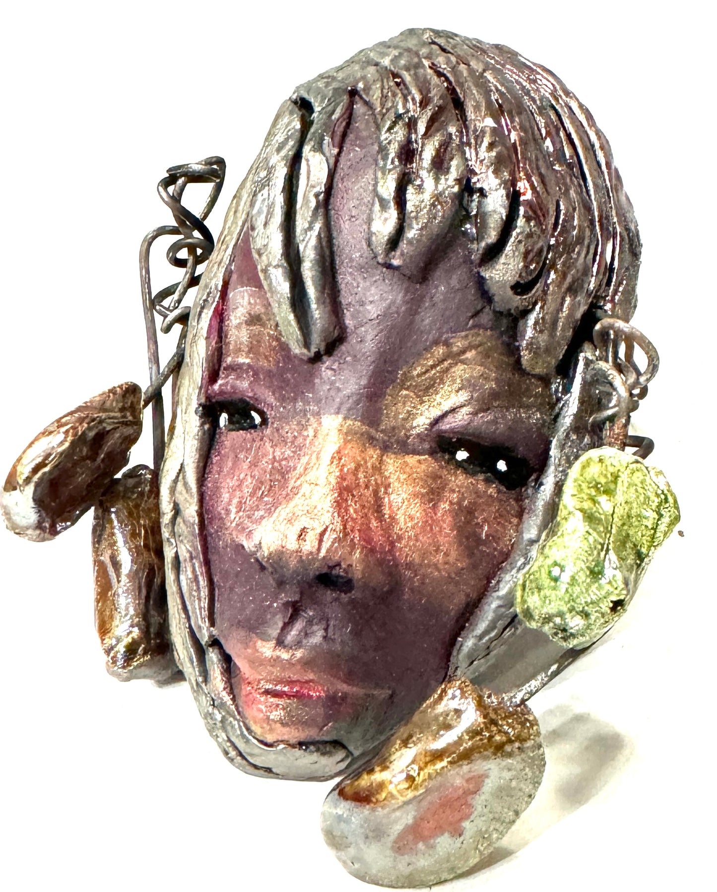 Monroe is 3" x 5" and weighs 5.5 oz. It is a Raku fired mask crafted from mixed media, with hand-crafted beads and 16 gauge wire used in its "hair". Whether inside or outdoors, it can be the perfect decoration for your home; the photo of Monroe was taken on a tree.
