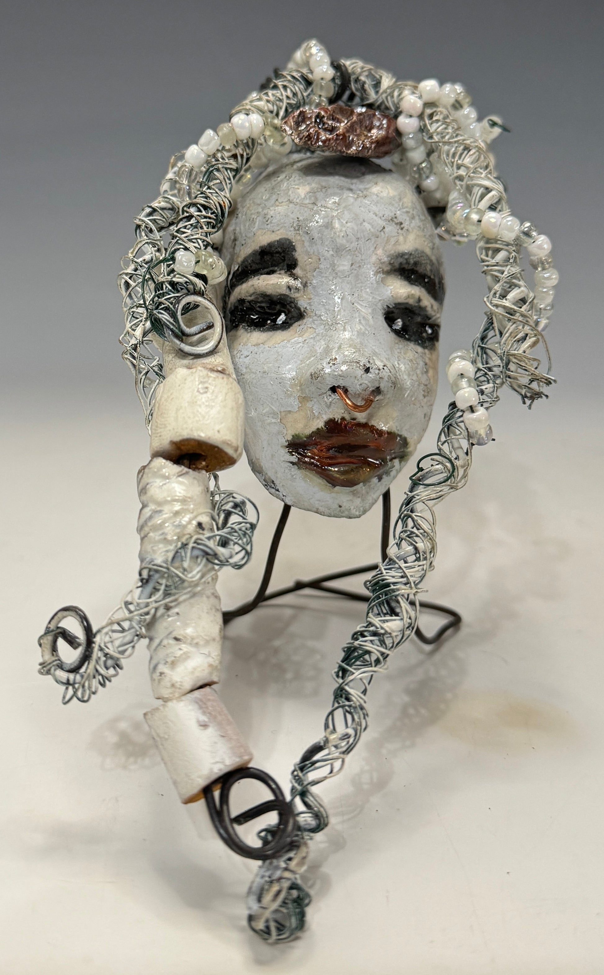Faye is an absolutely stunning 4" x 4", 4.2 oz. Raku-fired mask with a white complexion, intricate beaded hair, and a one-of-a-kind portrait setting of a majestic tree. She's sure to make a statement indoors or outdoors - an artful gift for nature admirers and décor fans alike!