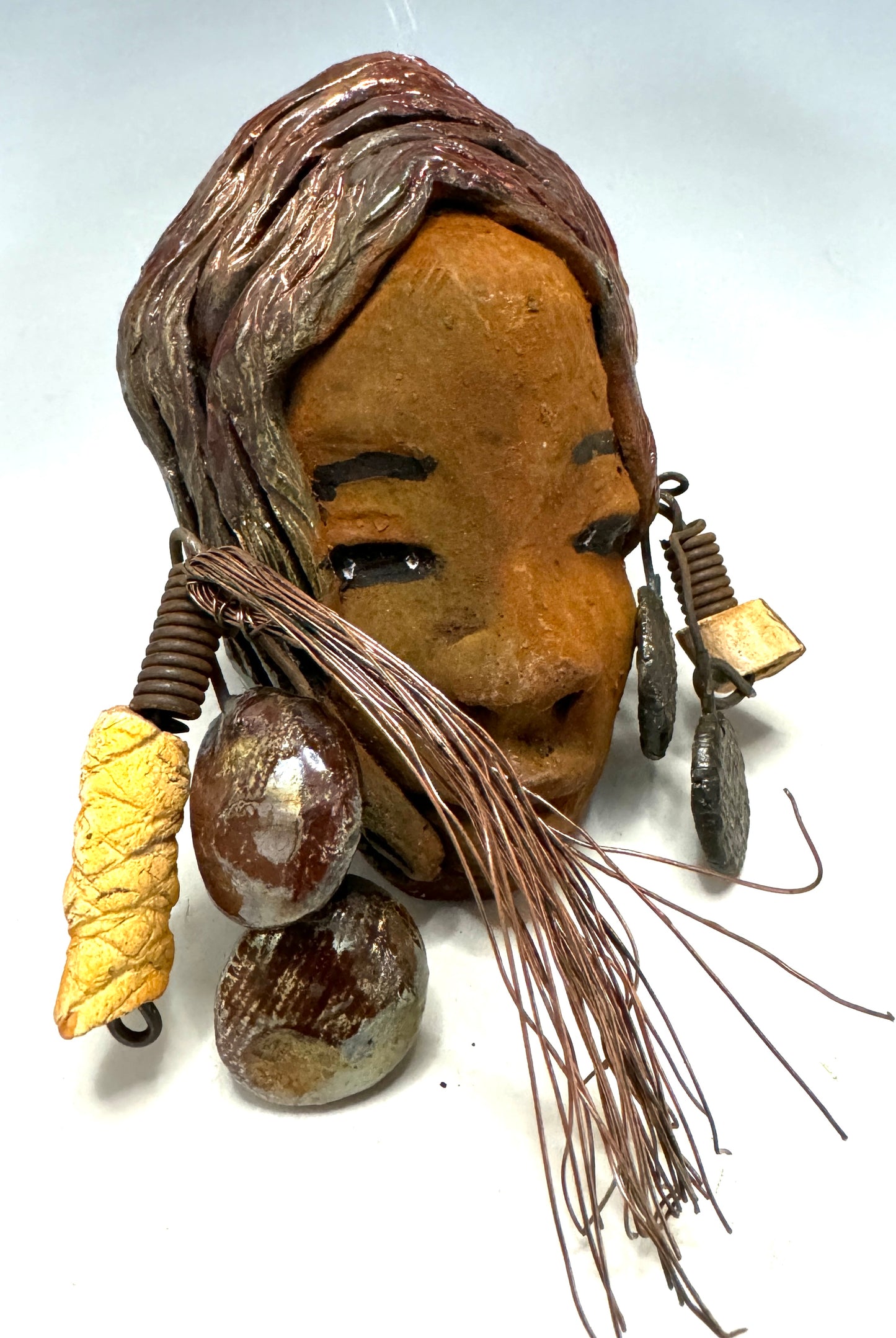 Marci boasts a beautiful honey-brown complexion, standing 5" x 7" weighs 6.2 ozs. and embellished with coils of wire and hand-made beads. Her hair is graced with a copper glaze and was photographed outside amongst the trees. But of course, she will look fantastic no matter where you decide to place her.