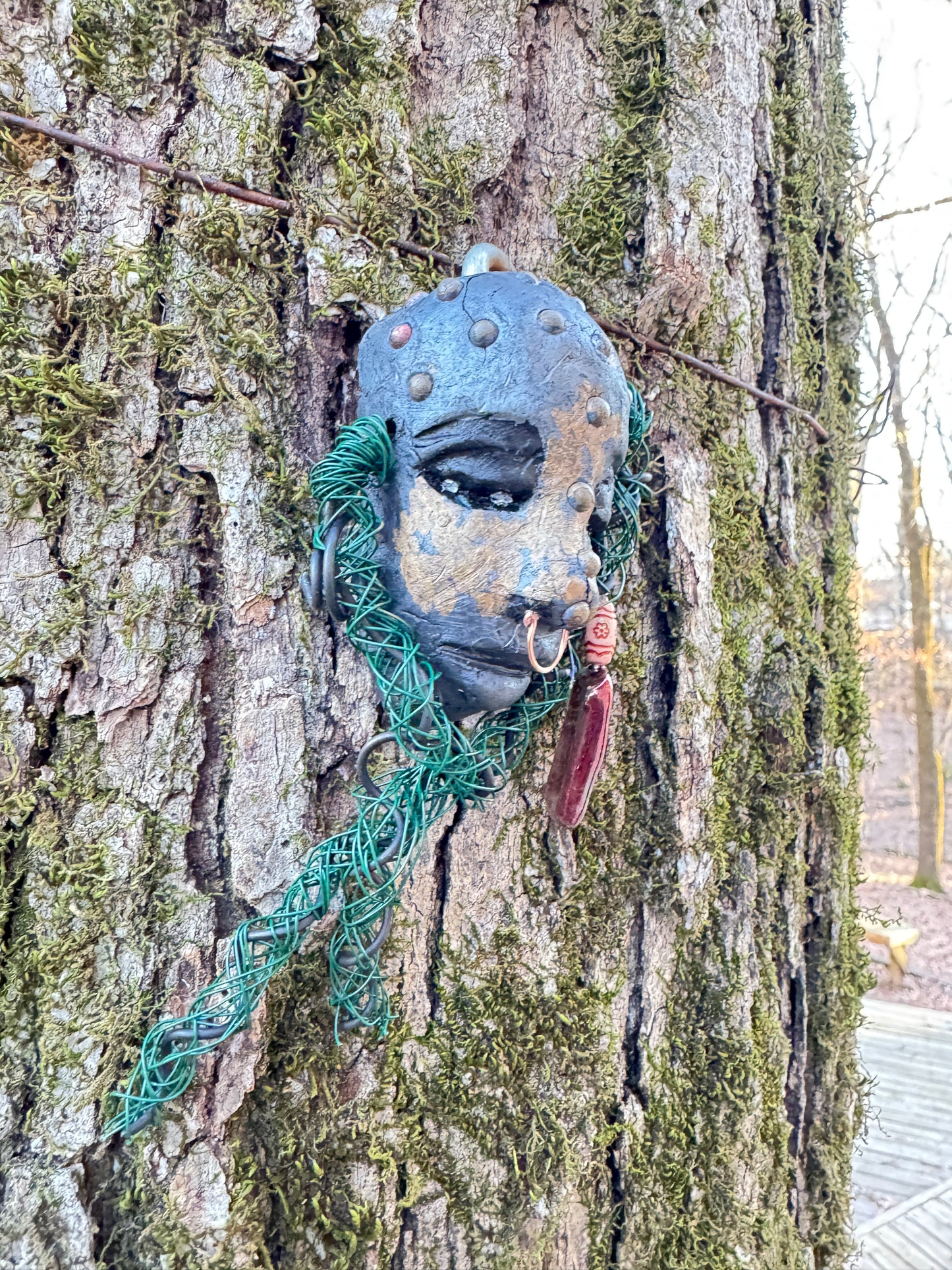 IIntroducing Addo, a unique raku fire mask made with a stunning combination of 24 and 16 gauge wire and embellished with intricate tribal beads in copper metallic. This 4 x 6" piece showcases over 15 feet of wire and can be elegantly displayed on a solid black or white surface. For a truly awe-inspiring effect, consider showcasing it against a lush, verdant forest backdrop.