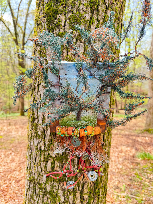 Discover the stunning Copper Cluster, measuring 18x15 inches, which blends 16- and 24-gauge wire with beautifully crafted Raku fire beads. As an added touch, a RAKU-fired hand-painted texture tile is mounted on a 8x7 wooden base. The sunlight streams through the lush copper foliage, evoking the feel of a refreshing spring day.
