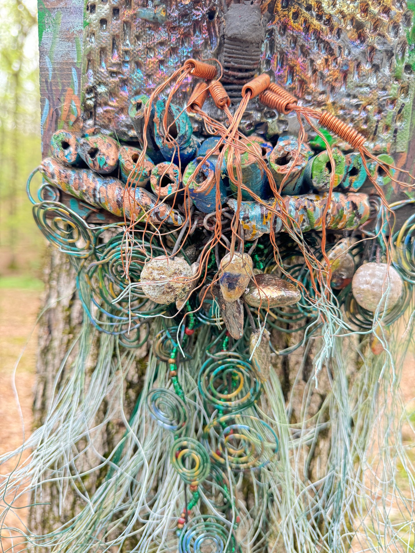 Explore the mesmerizing coil root of The Radiant Root, a mystical subterranean world showcased on a 20"x16" canvas embellished with a combination of 16- and 24-gauge wire and exquisite Raku fire beads, alongside a captivating RAKU fired and hand-painted texture tile resting on a 7"x5" wooden base, with a weight of 1.8 lbs. Immerse yourself in the vibrant shades of a summer sunset as the sunlight highlights the lush greenery.
