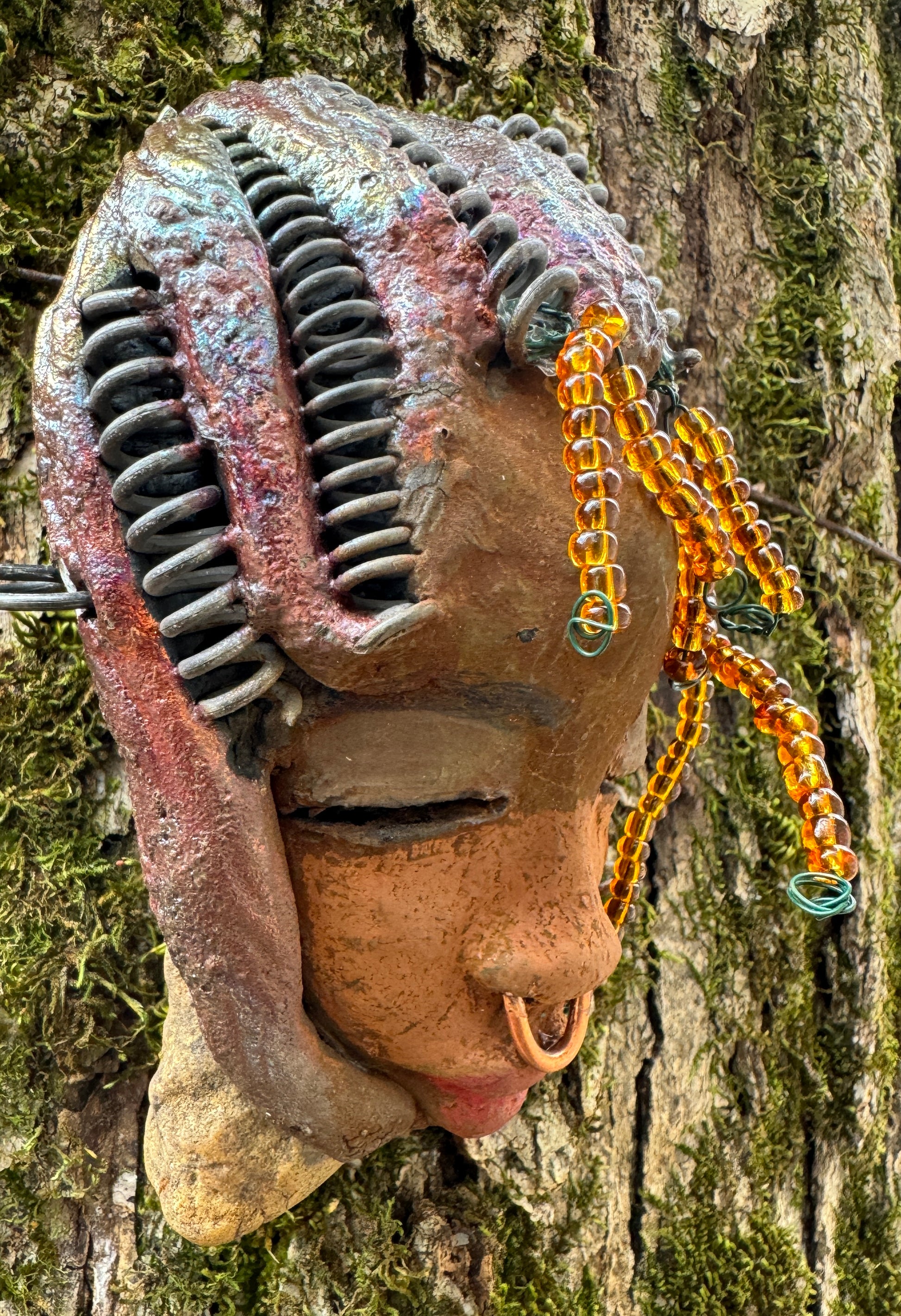 Kenya weighs 5 oz and is 4" by 3" in diameter. Her hair is coppered braided, her complexion is a light gray-blue, and her lips are black. She is a perfect item to start with from the HerDew mask collection. Shadowbox not included.