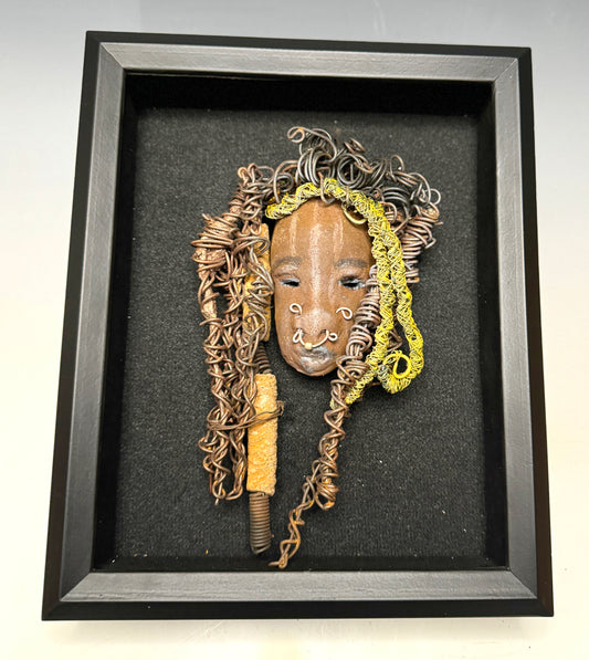 At 5" x 8" in size, Ike makes a stunning addition to walls, trees, and shadow boxes. His signature brown and amber braided hair is ornamented with handcrafted Raku beads, while his skin has a warm honey brown hue. Each piece is equipped with over 20 feet of top-notch 16 & 24-gauge wire in the hair. This fashionable sculpture will bring a modern flair to any room - simply place it in a shadow box and enjoy!