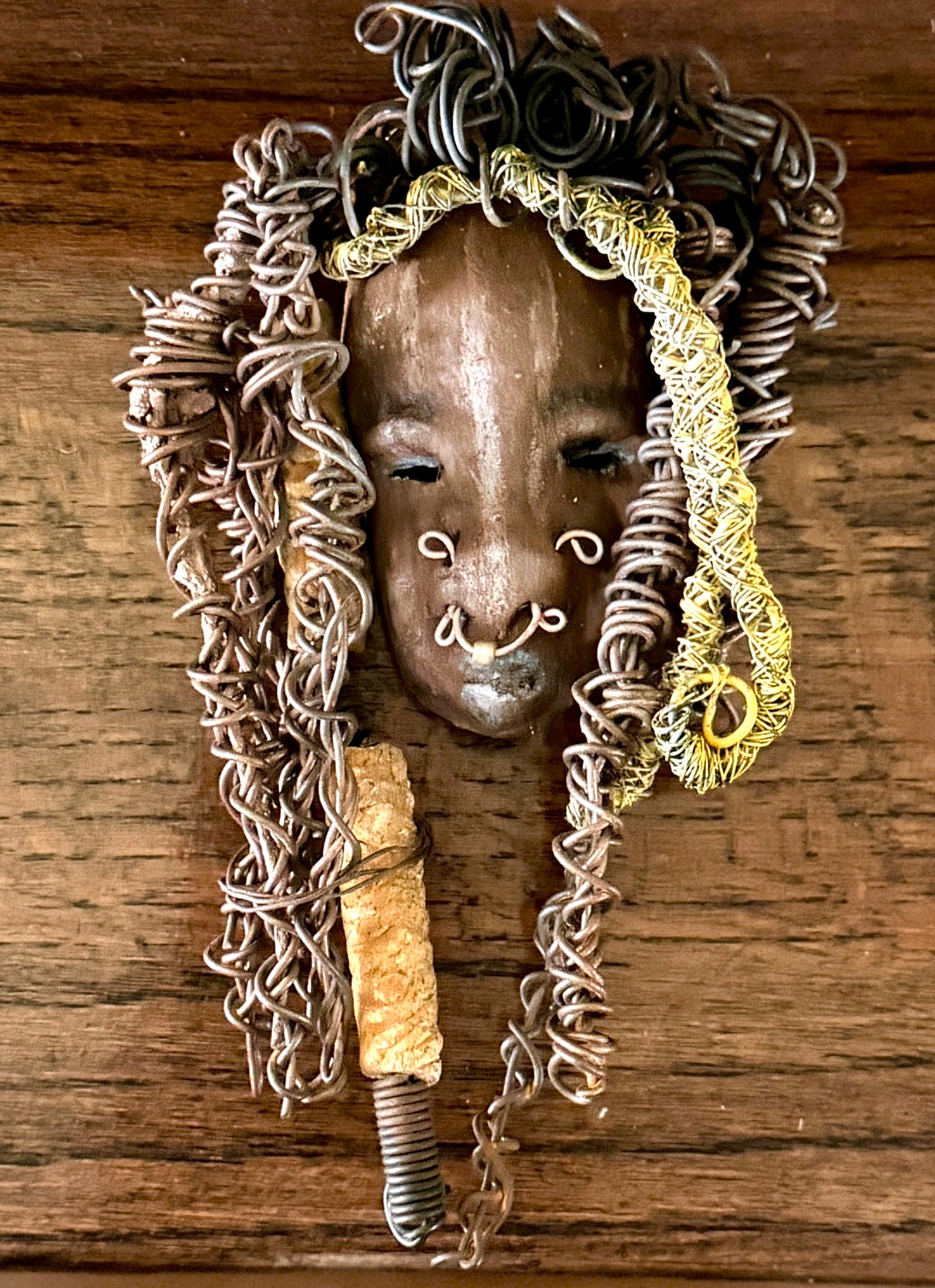 At 5" x 8" in size, Ike makes a stunning addition to walls, trees, and shadow boxes. His signature brown and amber braided hair is ornamented with handcrafted Raku beads, while his skin has a warm honey brown hue. Each piece is equipped with over 20 feet of top-notch 16 & 24-gauge wire in the hair. This fashionable sculpture will bring a modern flair to any room - simply place it in a shadow box and enjoy!