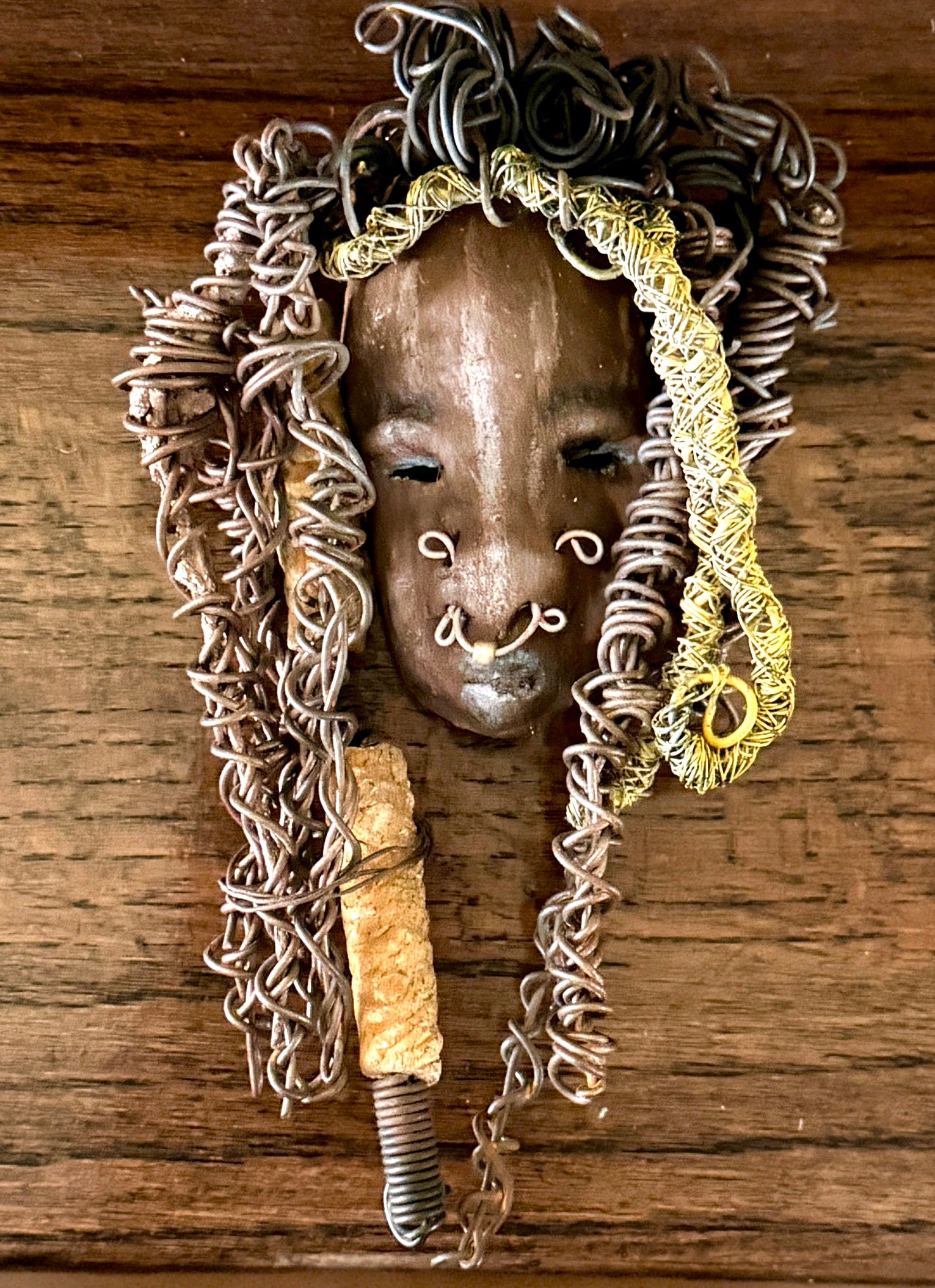 At 5" x 8" in size, Ike makes a stunning addition to walls, trees, and shadow boxes. His signature brown and amber braided hair is ornamented with handcrafted Raku beads, while his skin has a warm honey brown hue. Each piece is equipped with over 20 feet of top-notch 16 & 24-gauge wire in the hair. This fashionable sculpture will bring a modern flair to any room - simply place it in a shadow box and enjoy!