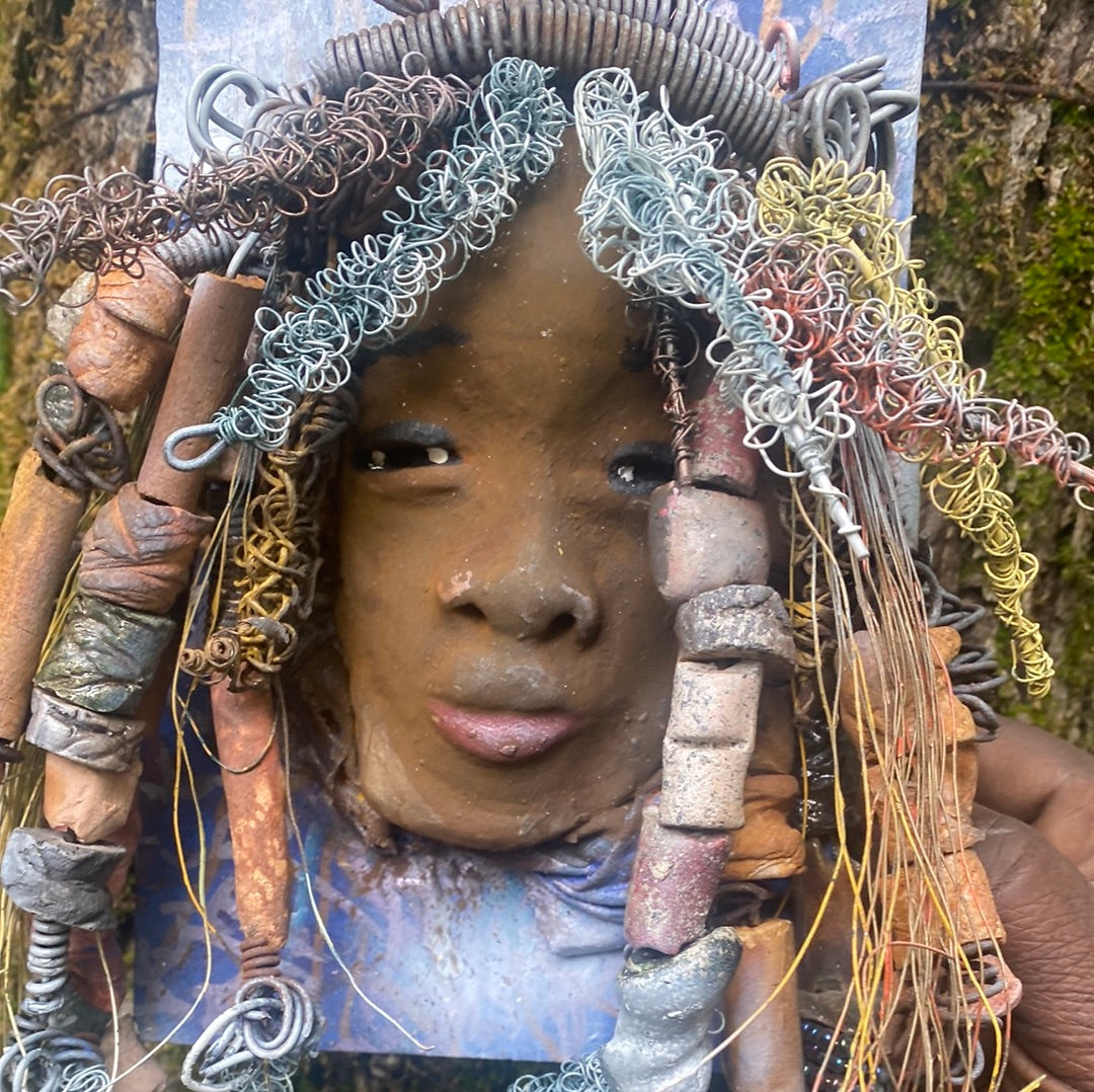 Valarie is mounted 5” x 8 x 1 and weighs 1.13 lbs. She has a contagious smile. Valarie face has a lovely honey brown complexion. She has over 20 handmade raku fired beads Over 60 feet of 16 and 24 gauge twisted wire for hair!