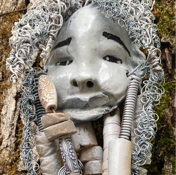 Wei has an off white complexion with off white lips. She is 6”x 8” and weighs 10 ozs. Wei has more than 10 handmade raku fired beads. Wei has over 70 feet of coiled 24 and 16 gauge wire hair.