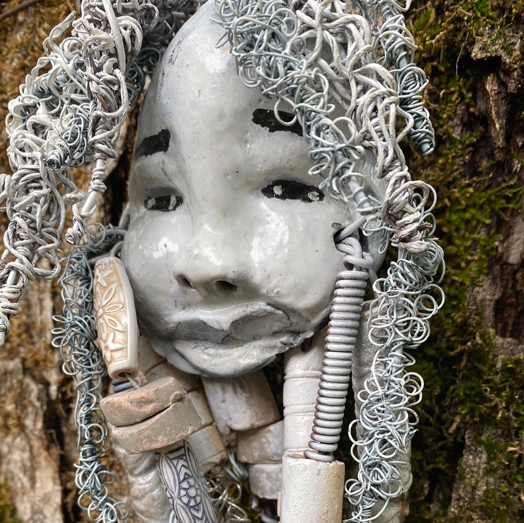 Wei has an off white complexion with off white lips. She is 6”x 8” and weighs 10 ozs. Wei has more than 10 handmade raku fired beads. Wei has over 70 feet of coiled 24 and 16 gauge wire hair.