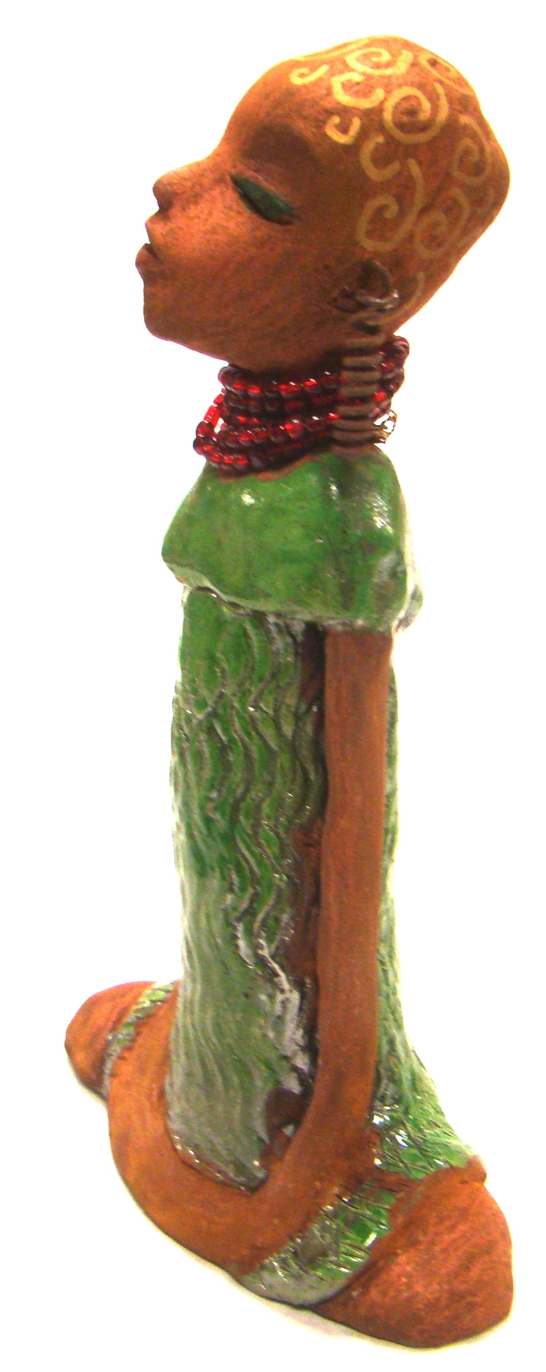 Amaya stands 10" x 6" x 2.5" and weighs 1.03 lbs. She has a lovely honey brown complexion. Her hair is drawn with spiral gold ink. Amaya long loving arms rest beside her alligator green dress. She wears a strand of ruby red beads with spiral wire ear rings. Amaya is a sophisticated lady that will grace your home. Free Shipping!