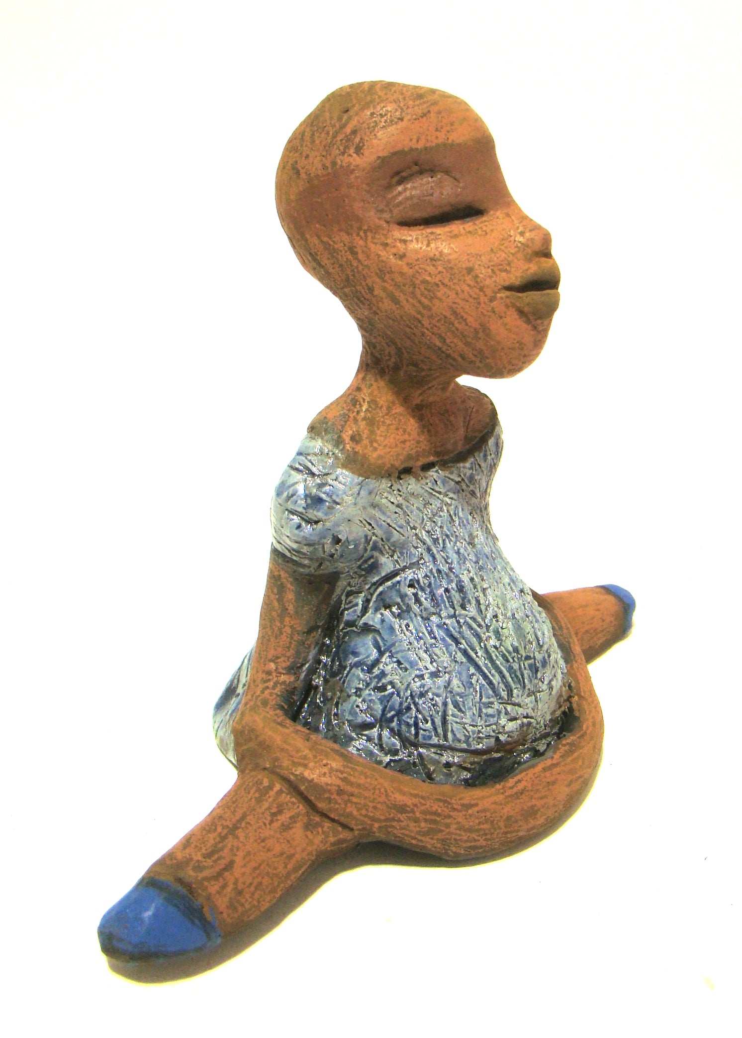 Vida sits 5" x 6" x 3" and weighs 10 ozs.     She is in a comfortable yoga pose.     Vida has a lovely honey brown complexion without hair.     Vida has a textured light blue with matching blue shoes.