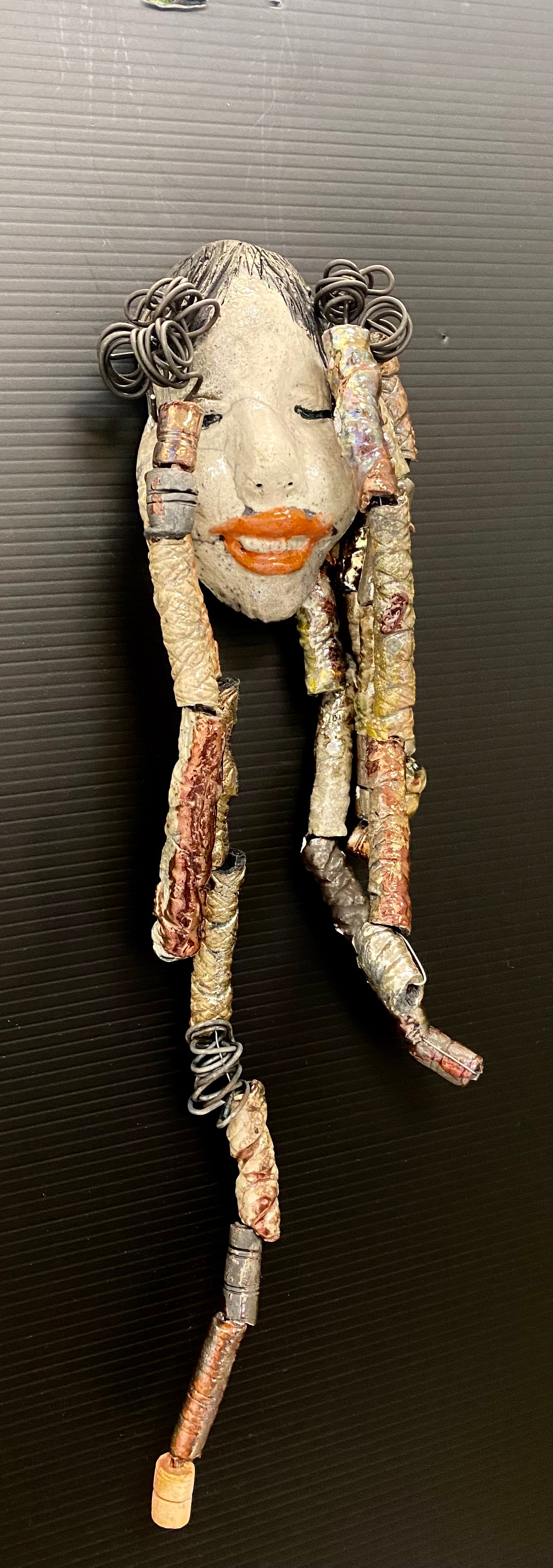 I started making art soon after seeing authentic African artwork at the Smithsonian Museum of African Art. I was in total awe. Trinity was inspired by my visit there. Trinity is 5”x 13” and weighs 11ozs. She has an off white complexion with ruby red lips. Trinity has five dreads of beads and spiral wire coils of hair. She is ready to be installed in your home!