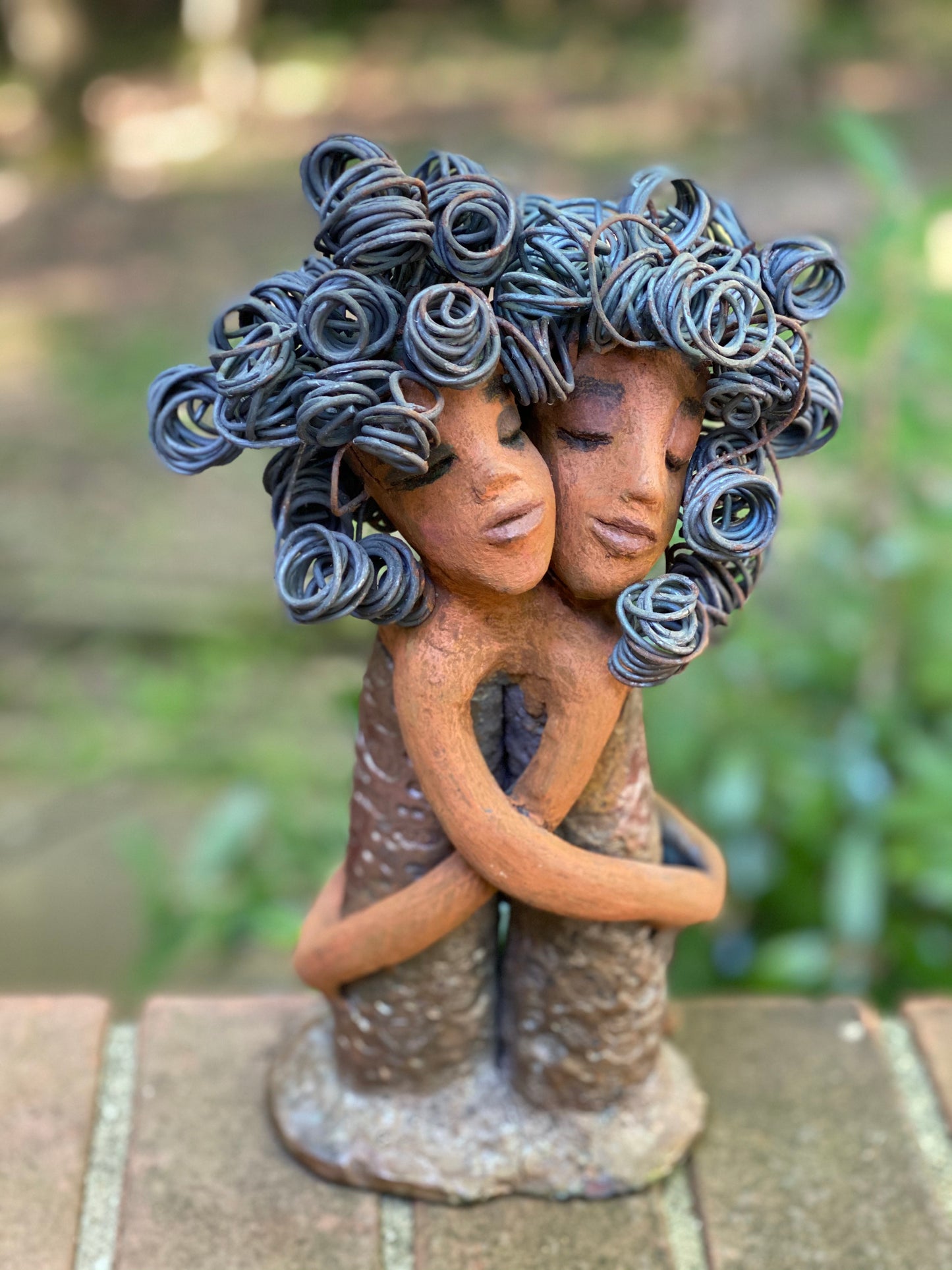 Sister Love is a raku fired sculpture. Raku is a specialized firing technique that involves high heat and open flames. Sister Love stands 11" x 5" x 3" and weighs 2.06 lbs. Combined they have over 45 feet of curled 16 gauge wire hair. The dresses are textured with an antique copper glaze. They have lovely honey brown complexions and long loving arms. Sister Love is inseparable! Give them a special place in your home. Free Shipping!