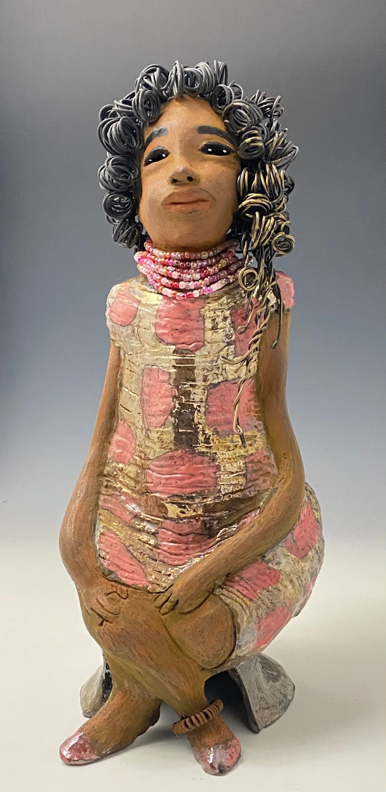 Meet Jasmine! Jasmine stands 18' x 6" x 5" and weighs 5.03 lbs. Jasmine has a lovely honey brown complexion. She has a shimmering copper red and gold dress with a red and off white beaded necklace. Jasmine is a tall girl with long loving arms. It took several hours to style Jasmine's 16 gauge two tone  wire hair! She looks as if she's dreaming or in disbelief.  I am proud of how Jasmine turned out! She appears to be a happy and sophisticated  lady!