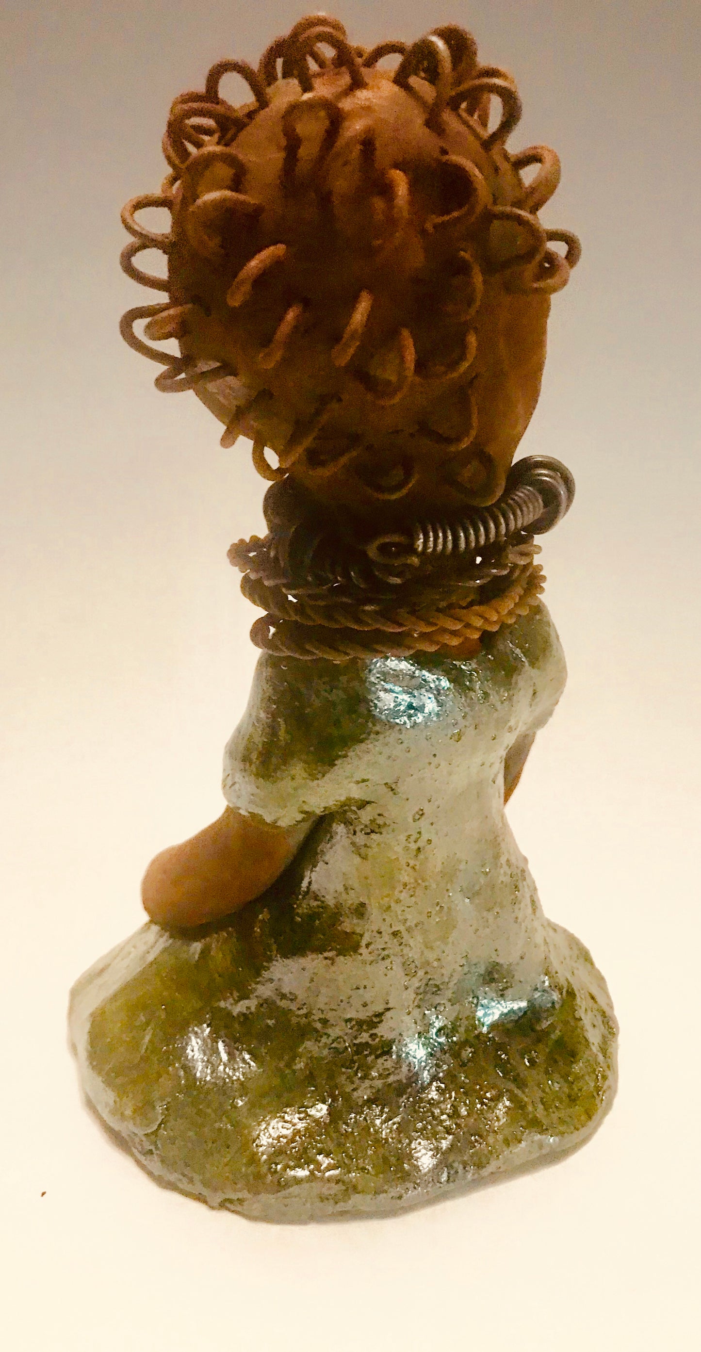 Nura stands 7.5" x 5" x 5" and weighs 1.06 lbs. She has a lovely honey brown complexion with reddish brown lips. She has a wire braided hairstyle. Nura has a colorful metallic green antique copper glazed dress. She wears spiral wire necklaces With her eyes wide opened, Nura has hopes of finding a new home.