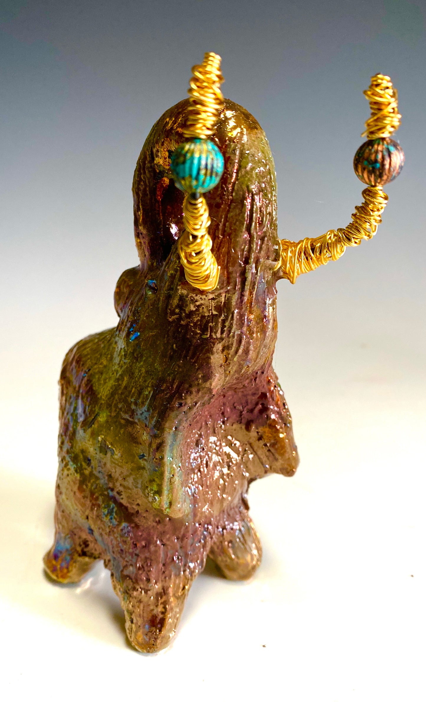 Raku Elephant Have you HERD!!!!!! Just one of these lovely Raku Fired Elephant will make an excellent gift for your friend, sorority or for your home’ special place centerpiece. 6" x 4" x 5" 14 ozs. Beautiful copper, green and gold metallic raku elephant Gold beaded tusk For decorative purposely only.