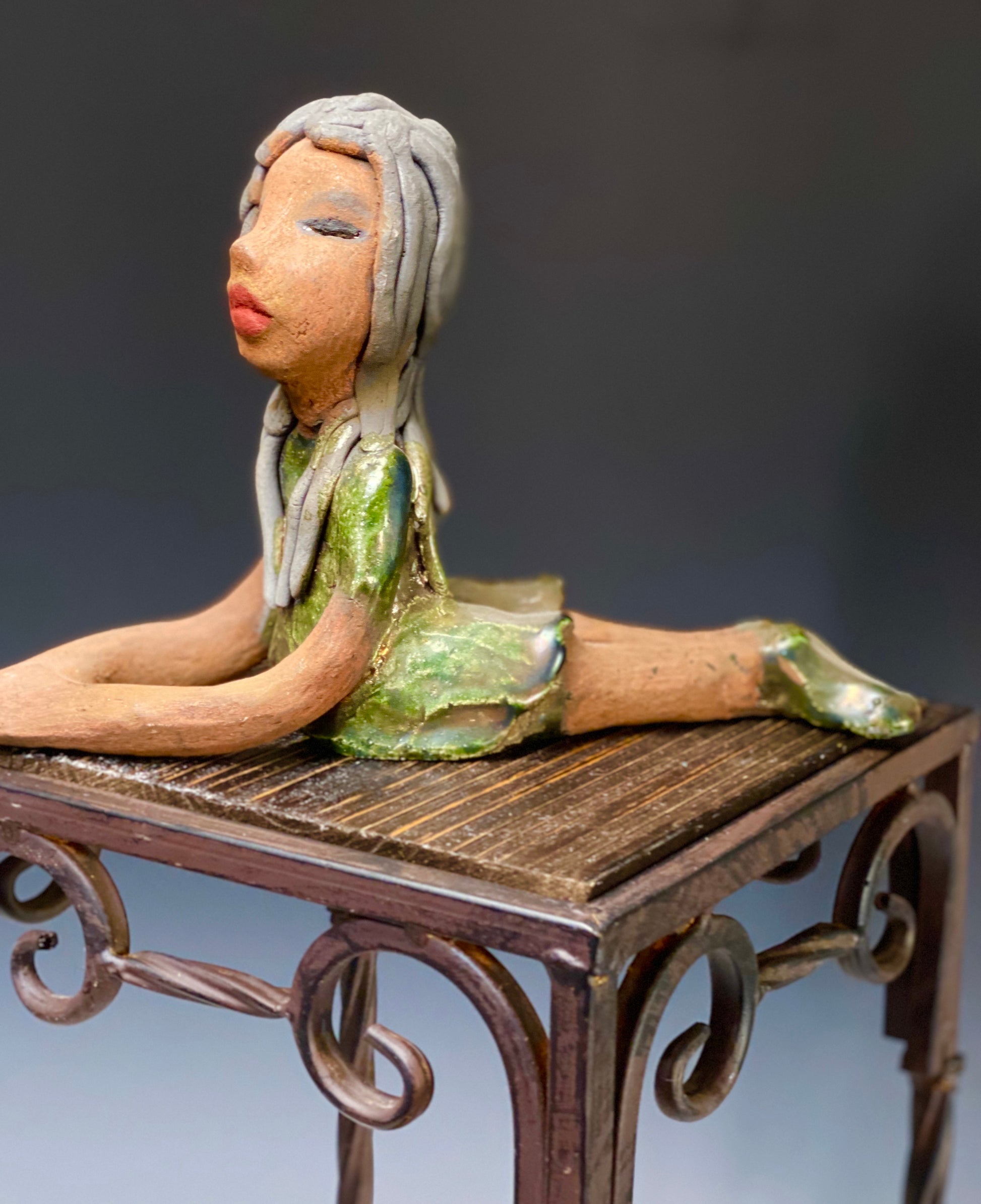 Meet Ashlie! Ashlie stands 6" x 3" x 8.5" and weighs 1.6 lbs. Ashlie has a lovely copper brown complexion and smokey black hair. She wears a metallic copper dress and shoes. Her long loving arms are placed in front of her as she rest. Give Ashlie a nice spot to relax in your home!