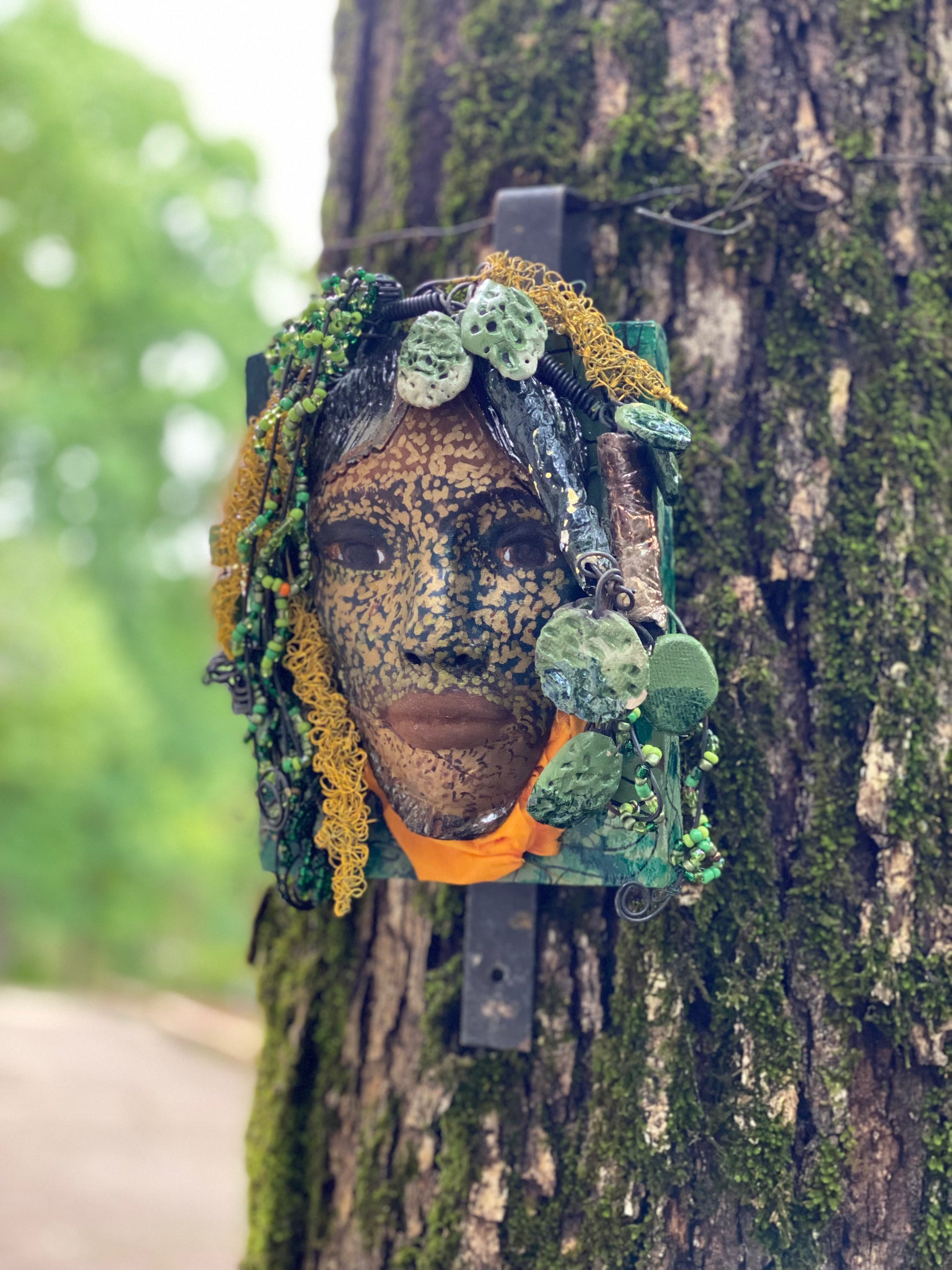 Casey is one of a new 2022  series of tribal masks that are mounted on wood. I started making art soon after seeing authentic African artwork at the Smithsonian Museum of African Art. I was in total awe. Casey is 6” x 7 x 1 and weighs 1.13 lbs.  She has a contagious smile. Casey's face is speckled gold. 12 handmade raku fired beads Over 60 mini 6mm multi colored beads  Over 60 feet of 16 and 24 gauge twisted wire for hair! Over two weeks to complete! Casey is ready to be mounted inside or outdoors!