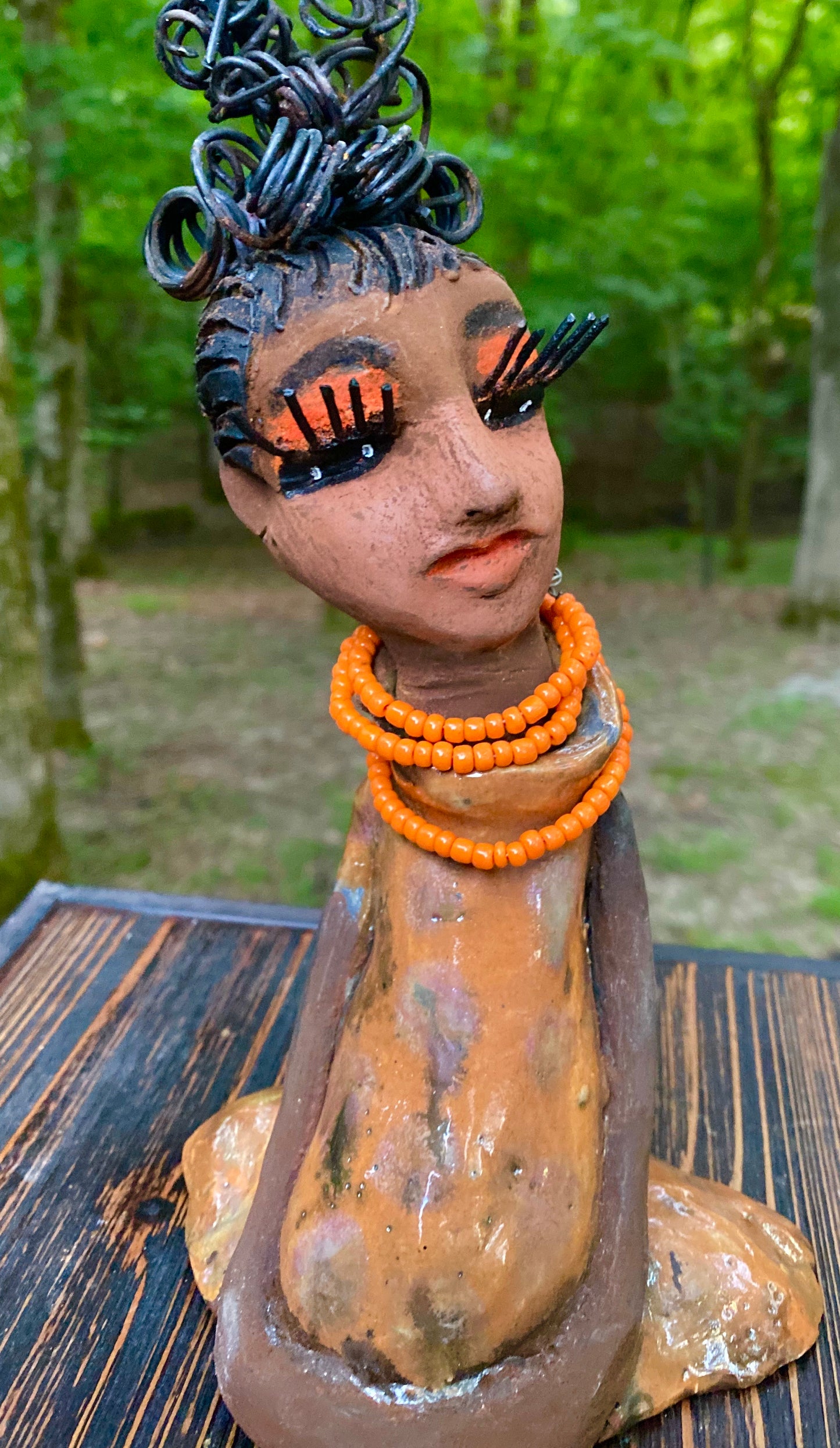 Meet Abimbola ! Abimbola stands 7' x 4"x 2" and weighs 1.3 lb. She has bright eyes and a nice honey brown complexion Abimbola  has over 5 feet of 16 gauge wire hair wrapped in a bun. Her long trademark arms rest at her side. Abimbola dress is a loving glossy orange mix with copper flashes. Abimbola is waiting for you to invite her into your home!